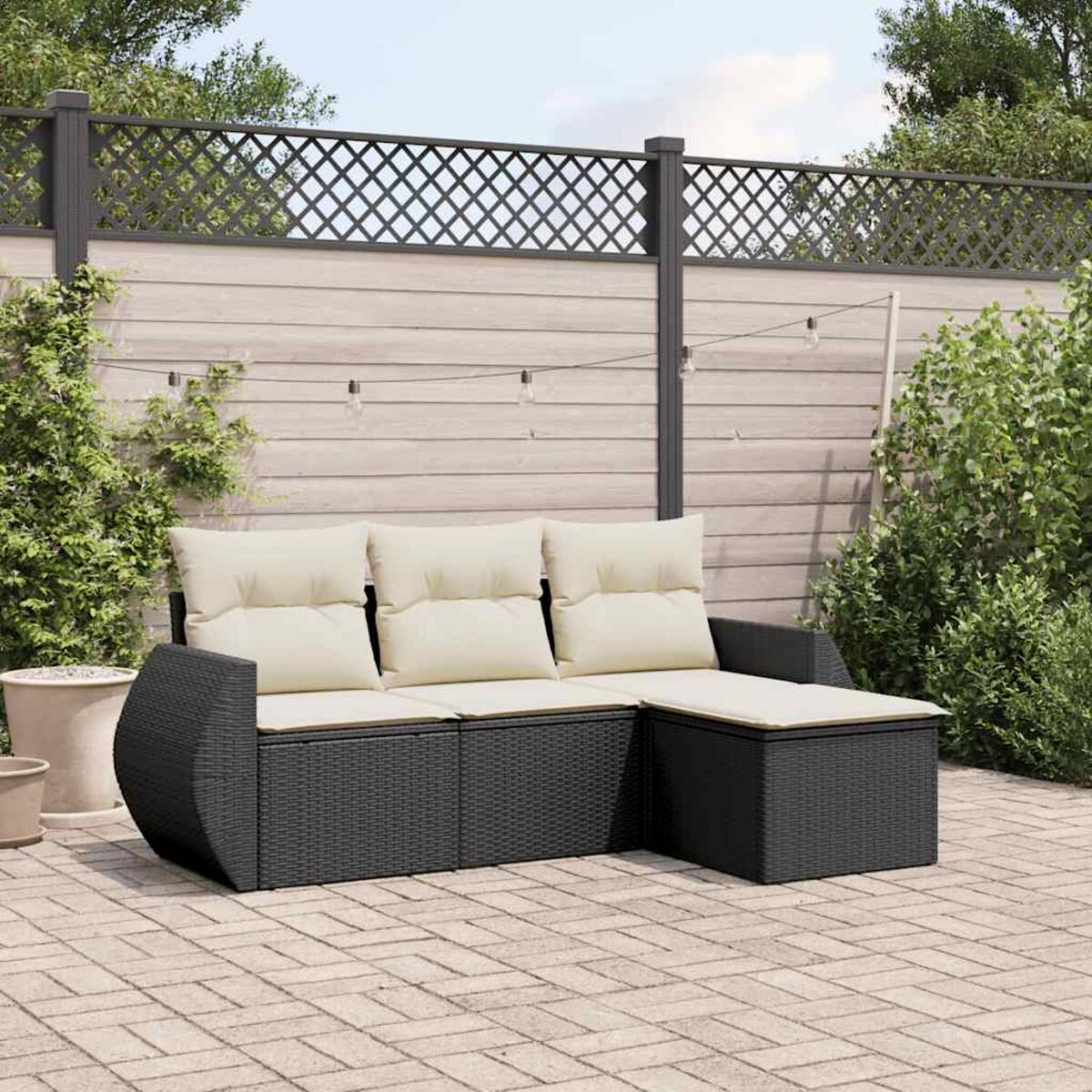 Schwarzes Outdoor-Ecksofa mit beigen Kissen auf einer Ziegelterrasse, mit Zaun im Hintergrund.