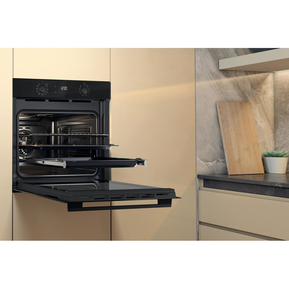 Forno con porta aperta e vassoi. Scena cucina con tagliere e pianta. Tonalità beige.