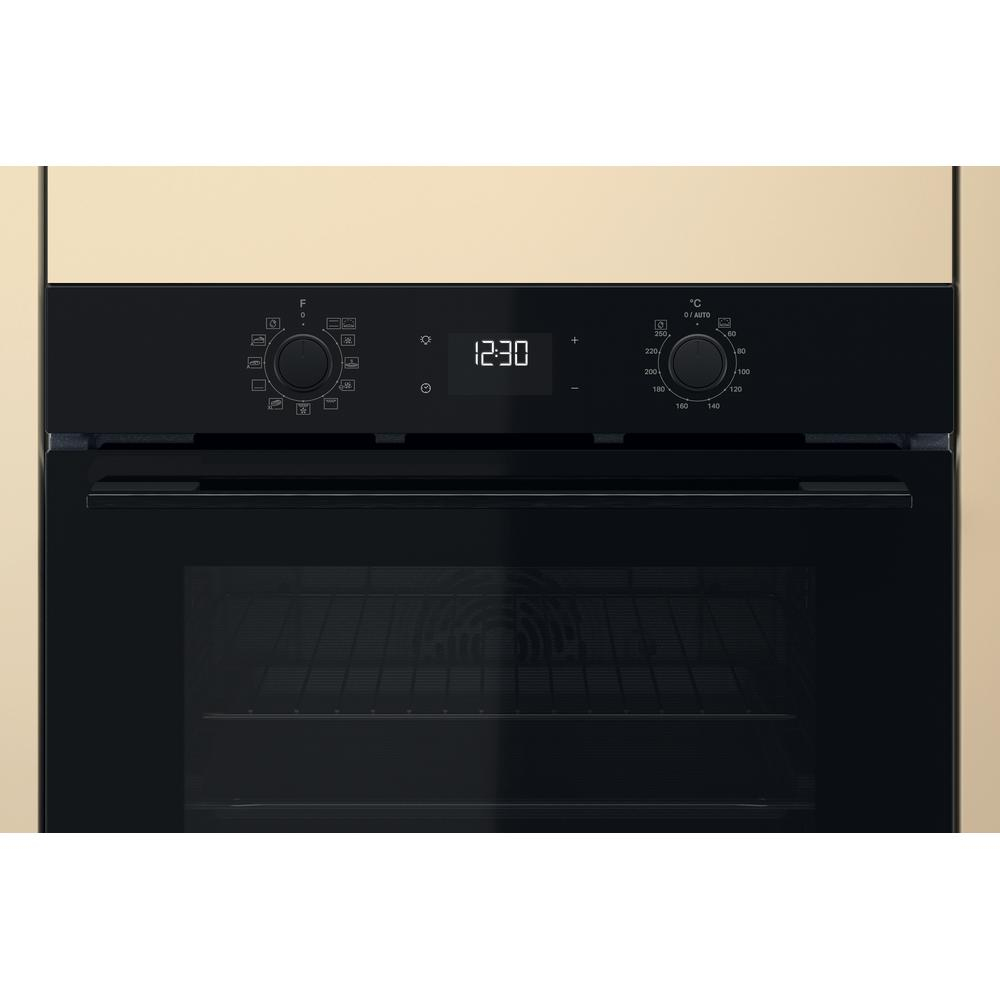 Primo piano del pannello di controllo di un forno nero. C'è un display dell'orologio, pulsanti e quadranti. Cornice beige.