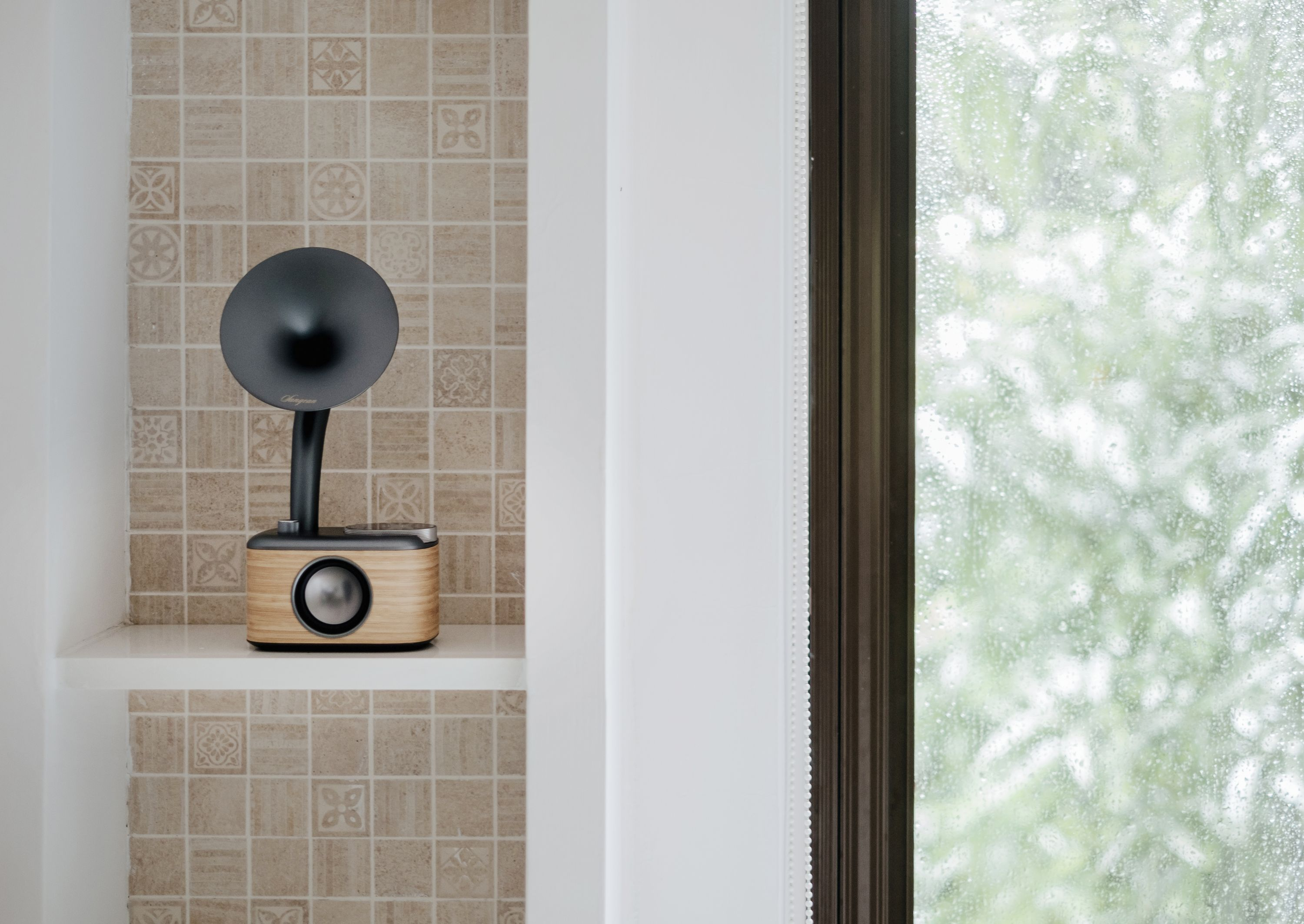 Lautsprecher im Retro-Stil auf Regal, beige und schwarz, Fenster im Hintergrund.