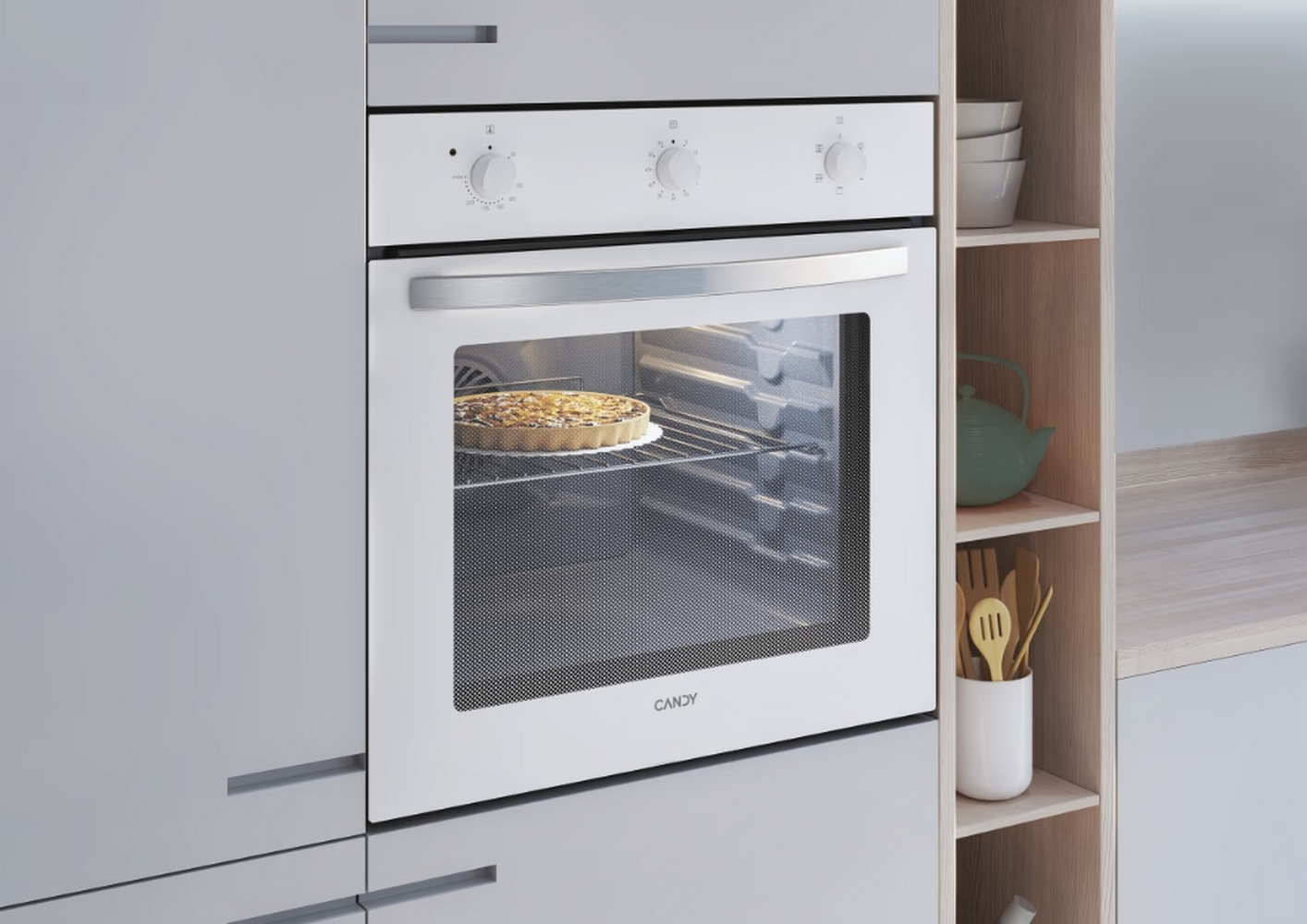 Forno bianco con torta all'interno, in un ambiente cucina. Armadietti e mensole visibili, con utensili e una teiera.