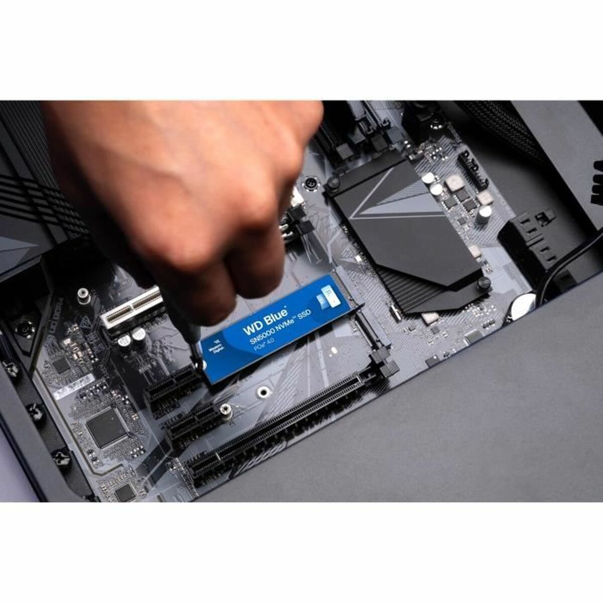Ręka instalująca dysk SSD WD Blue SN5000 NVMe w płycie głównej.