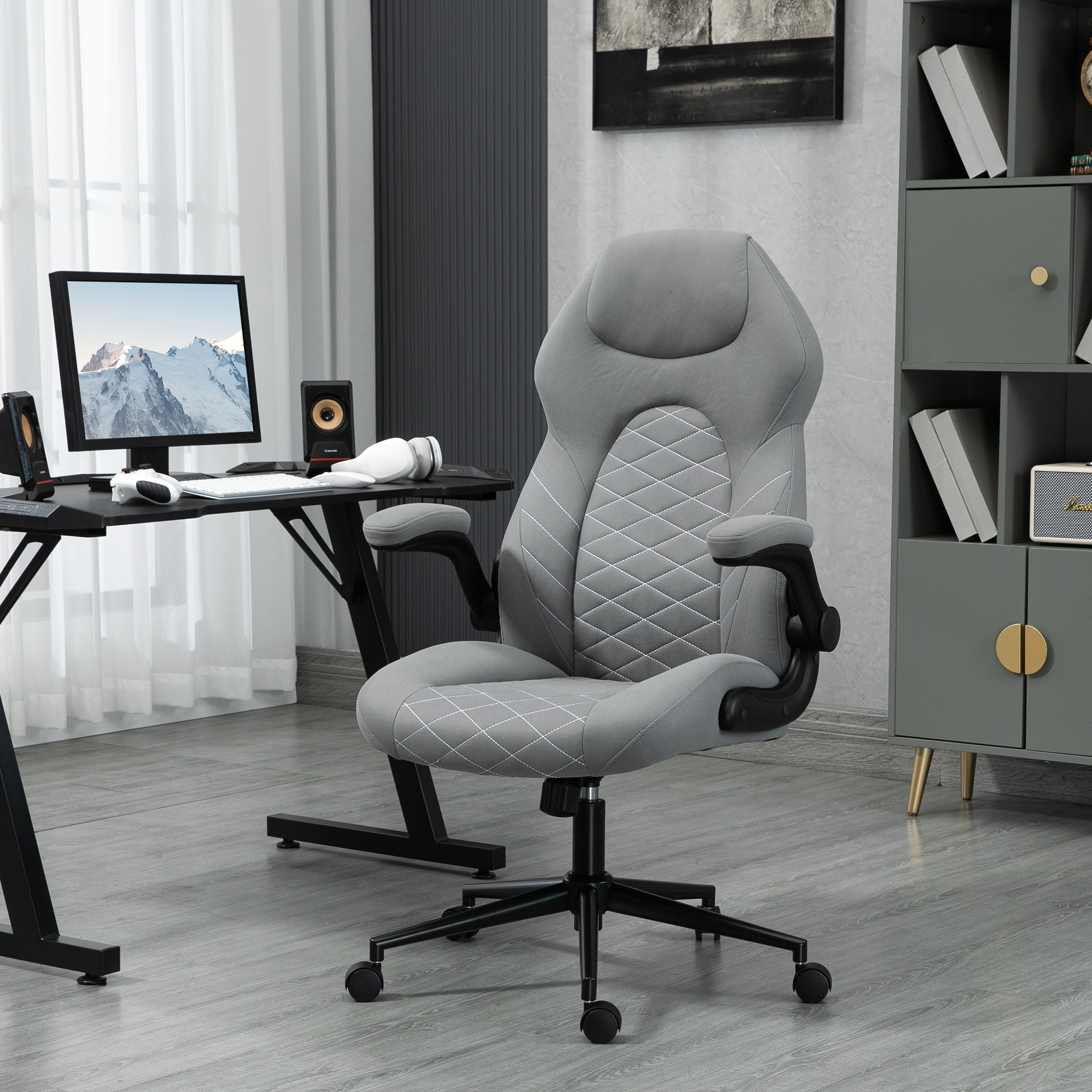 Büro-Setting mit grauem Stuhl, Computer und Regalen. Der Stuhl hat ein weißes Rautenmuster.