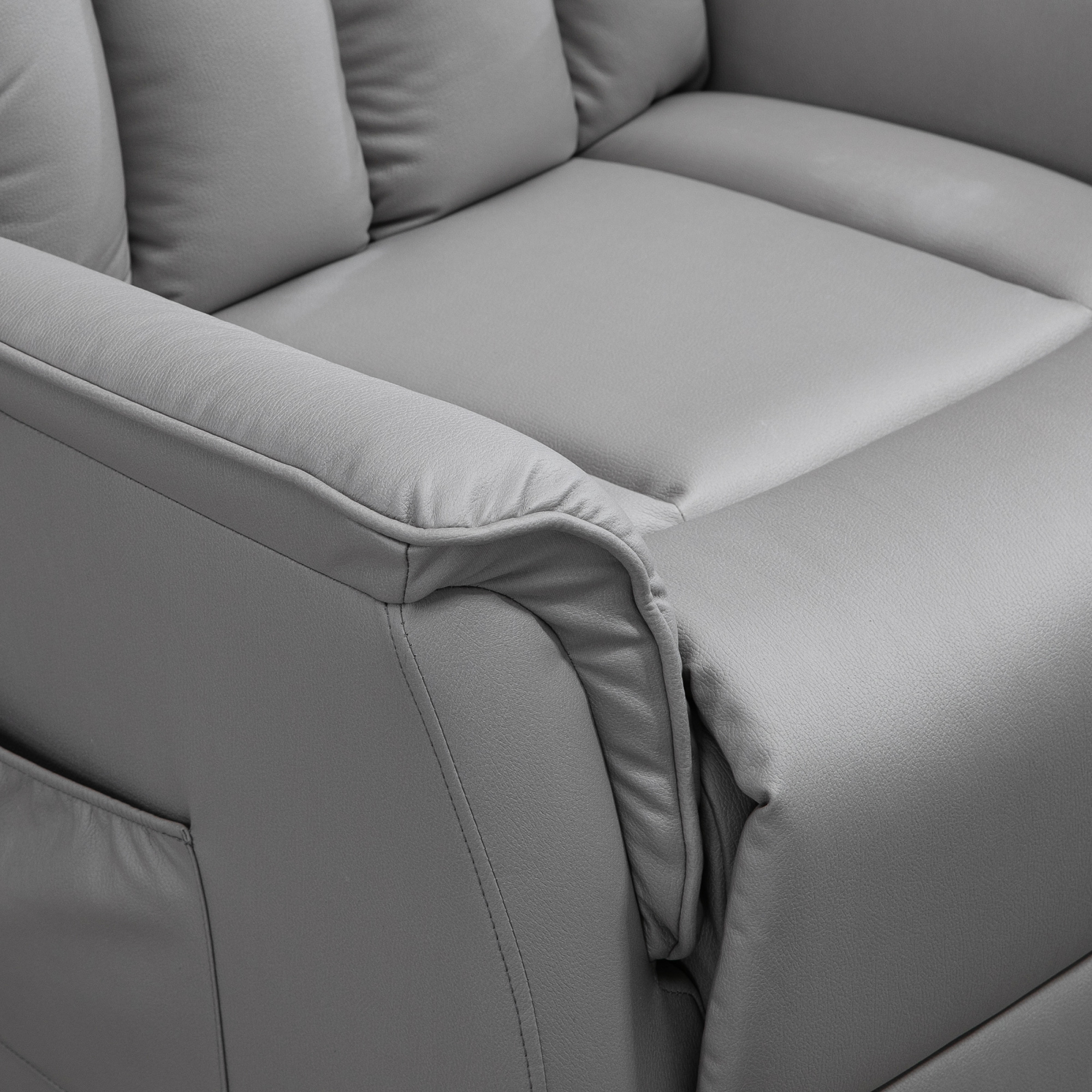 Nahaufnahme der Armlehne und Kissen eines grauen Ledersofas mit Nahtdetails.