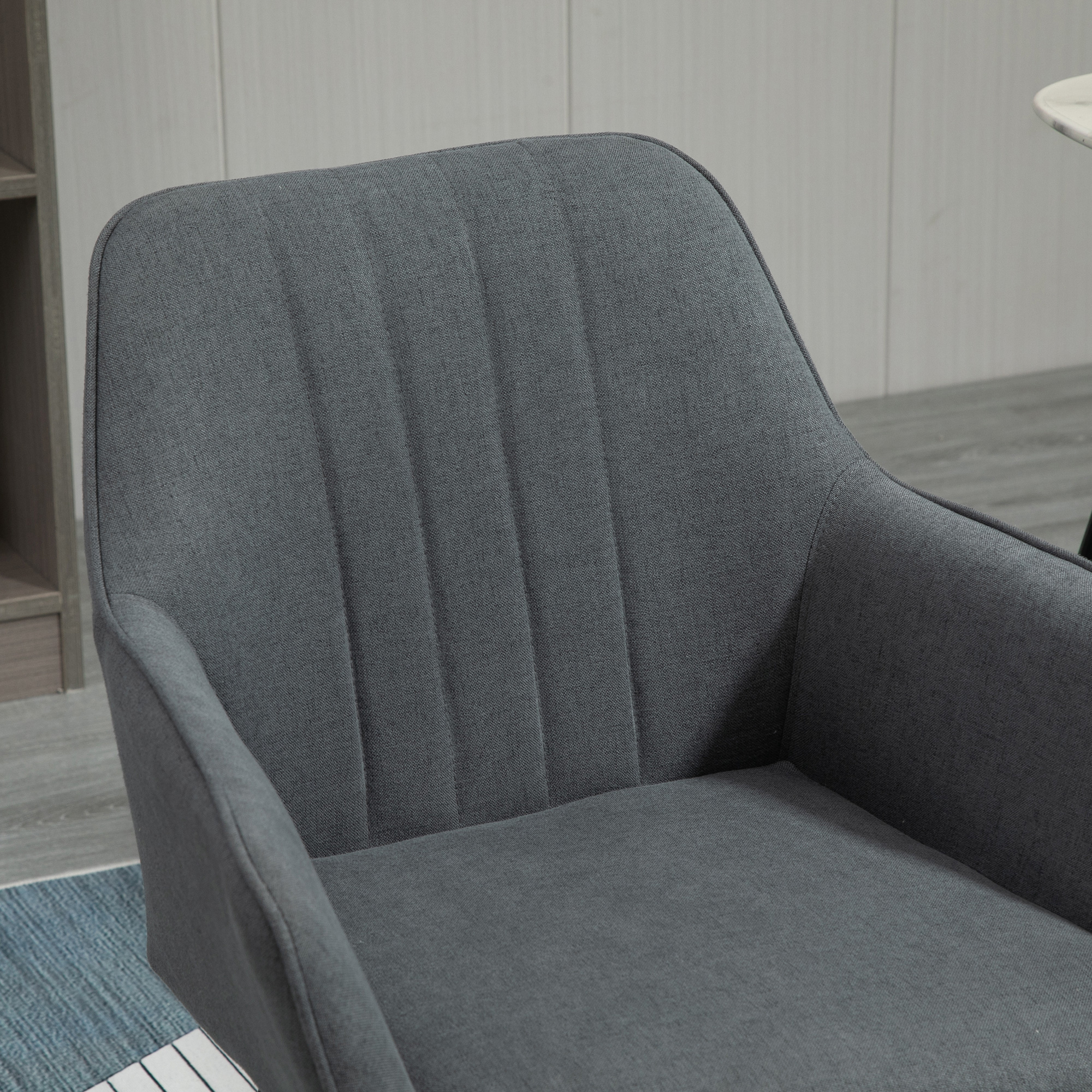 Silla tapizada gris. Primer plano del respaldo y asiento de la silla. La silla tiene líneas cosidas verticales.