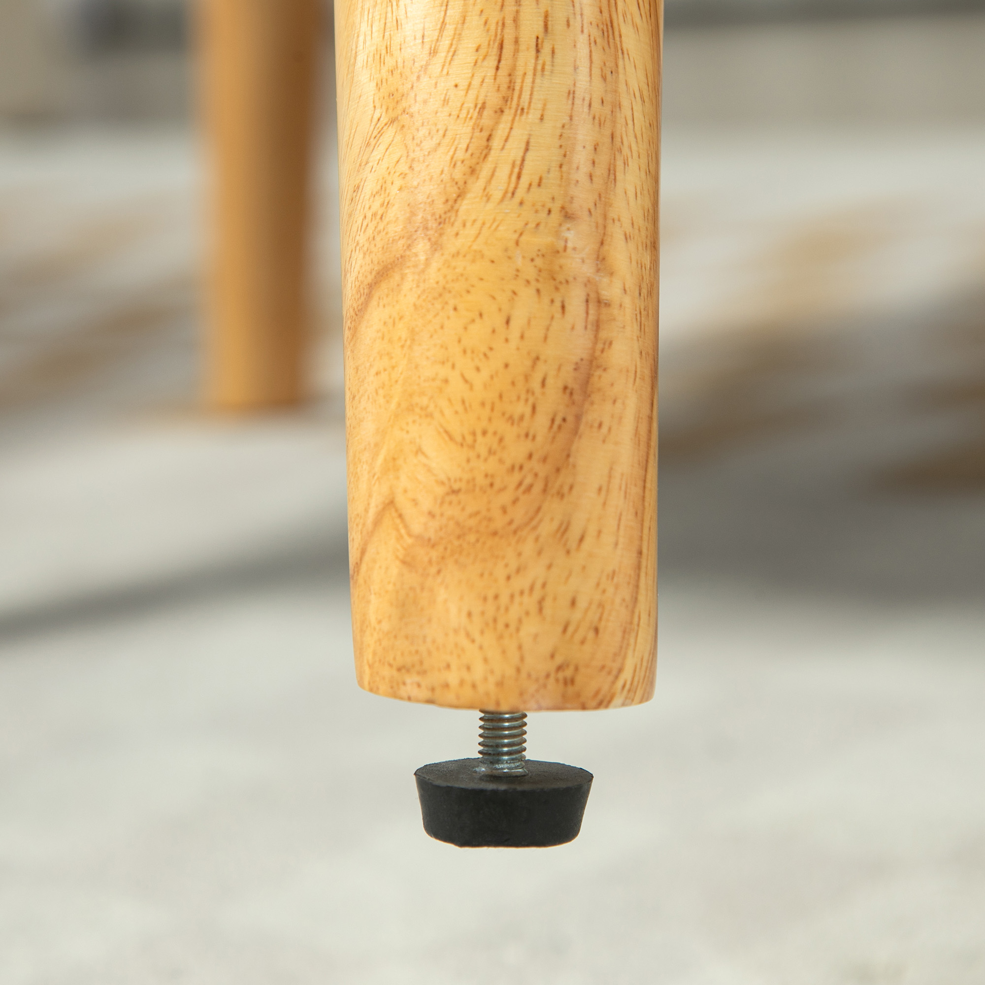 Nahaufnahme eines hölzernen Tischbeins mit Gummifuß. Das Holz hat eine hellbraune Farbe.