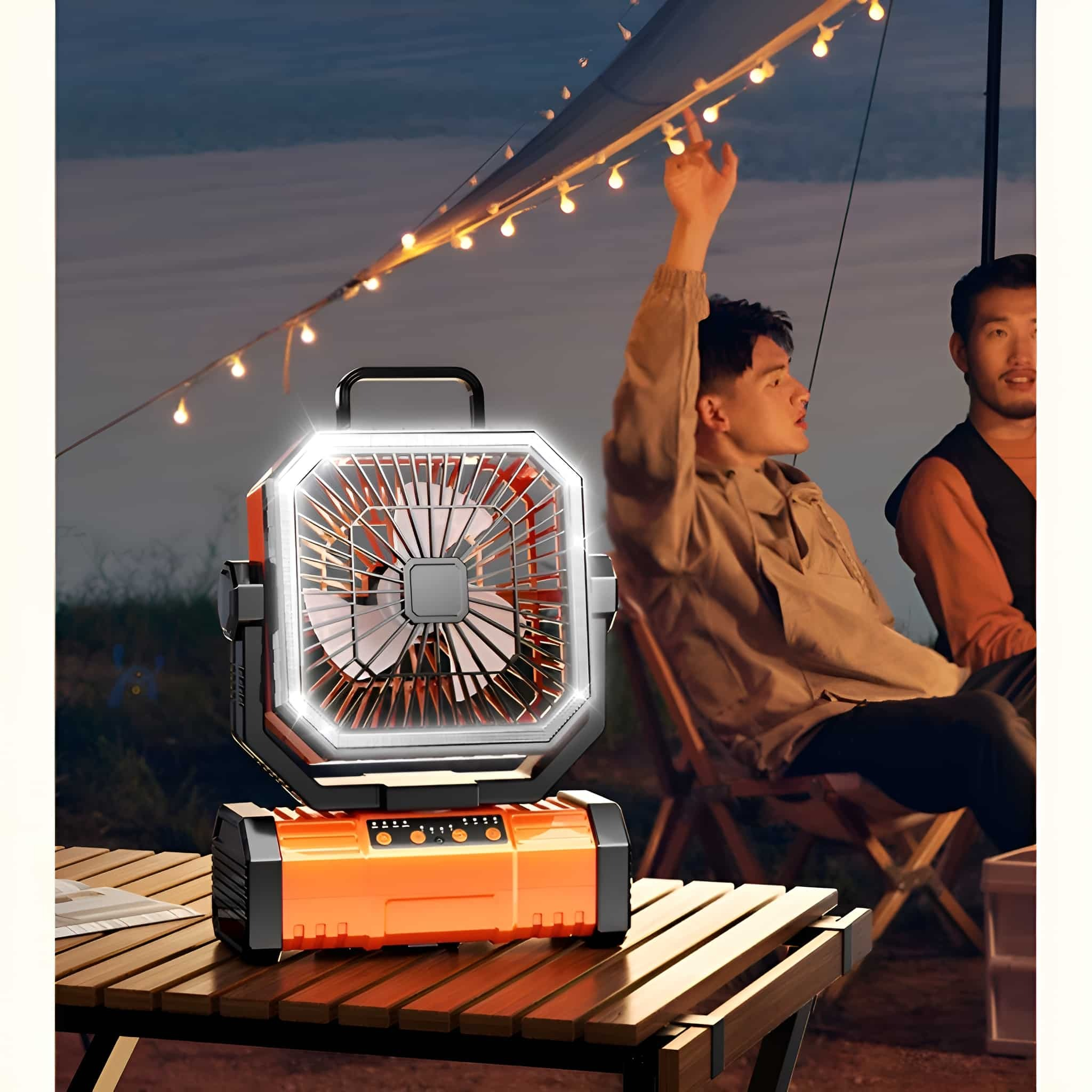 Ein orangefarbener Ventilator auf einem Tisch. Zwei Männer sitzen in der Nähe eines Lagerfeuers mit Lichterketten.