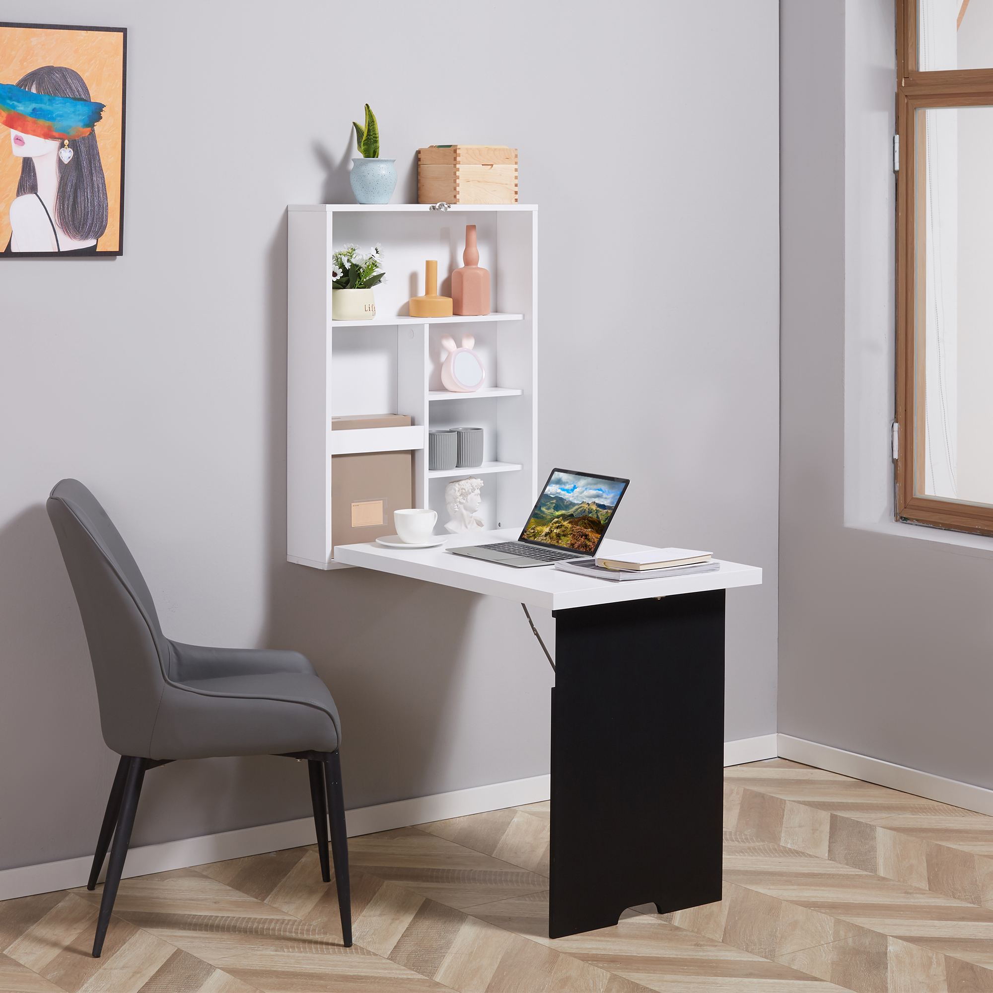 Ein weißer, an der Wand befestigter Schreibtisch mit Regalen, einem Laptop und Dekorationsartikeln steht vor einer grauen Wand.