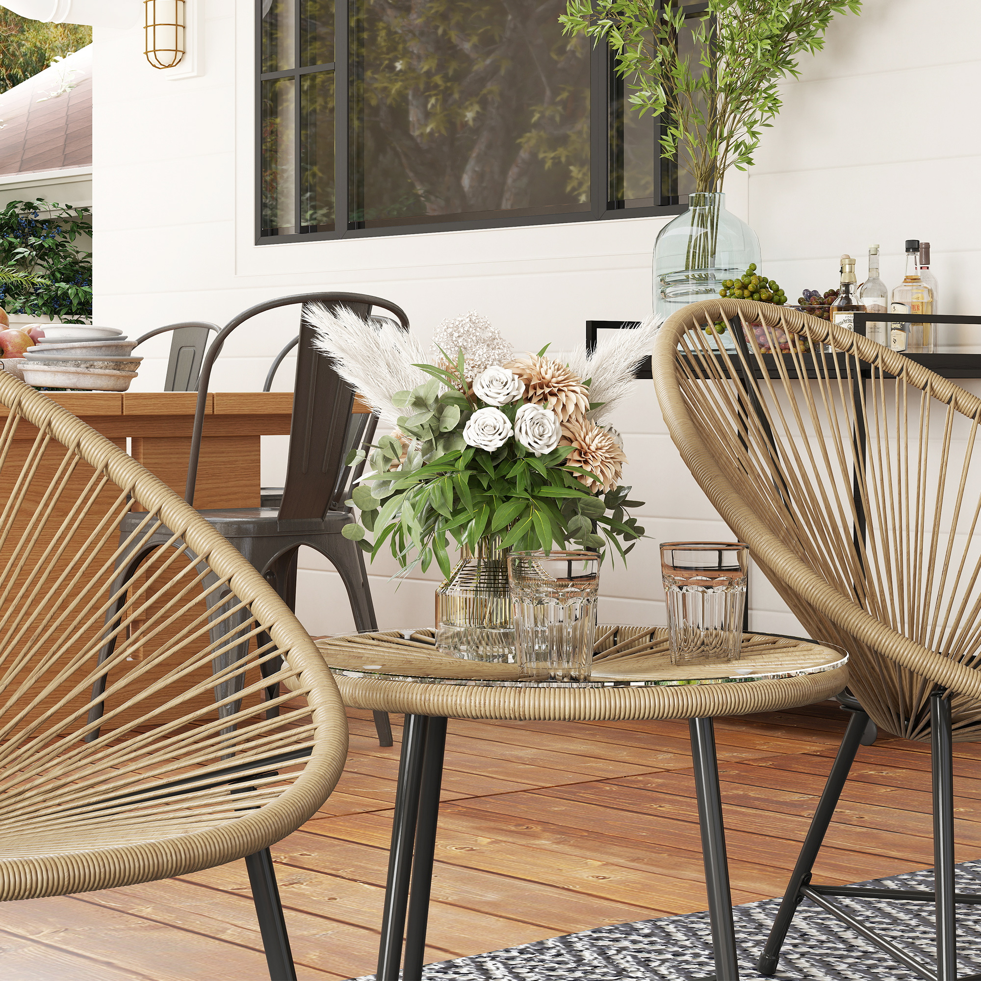 Eine Terrasse mit Stühlen, einem Tisch und Blumen. Es gibt eine Holzterrasse und ein weißes Haus.