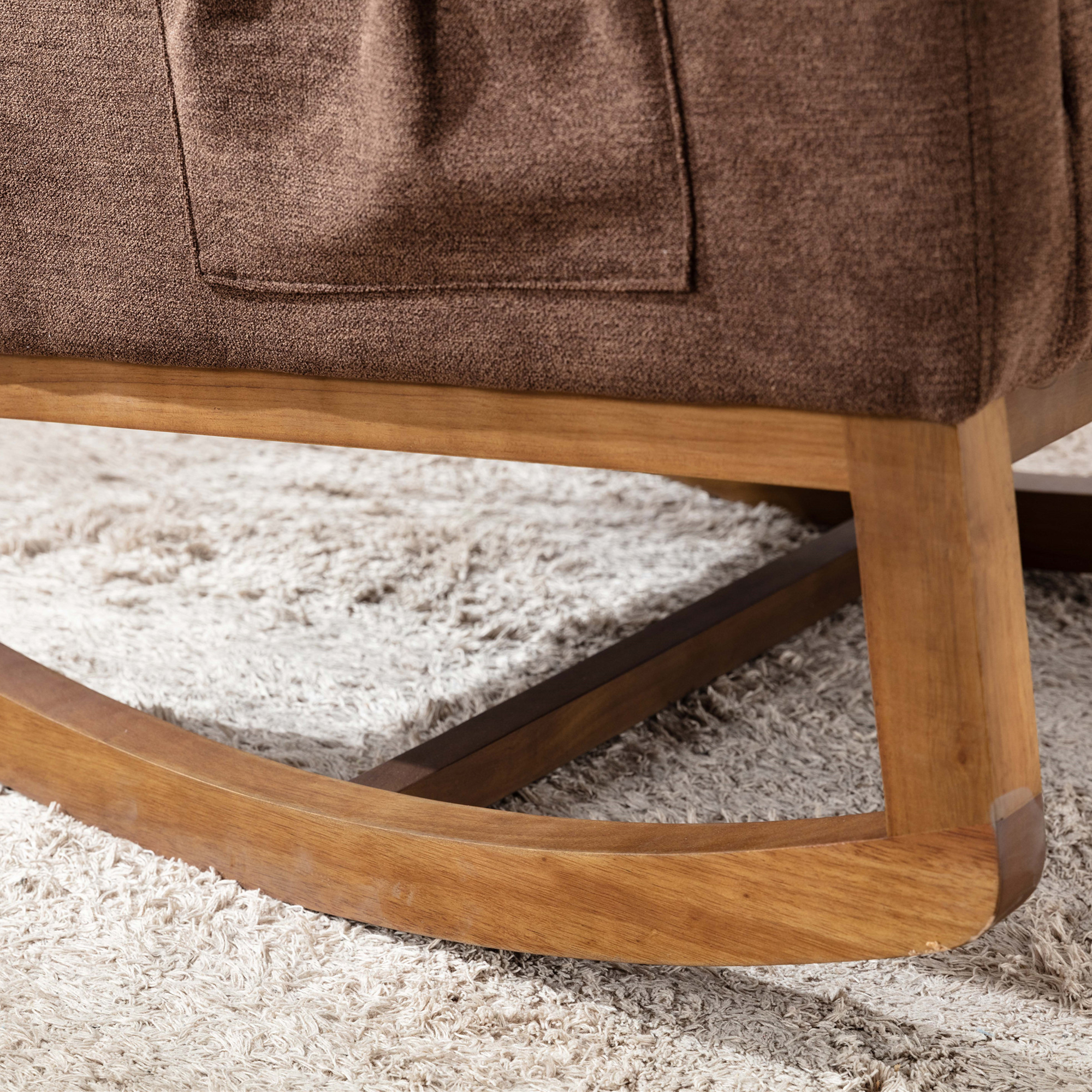Nahaufnahme der Holzbasis eines braunen Schaukelstuhls und des Teppichs, auf dem er steht. Der Stuhl hat eine Tasche.