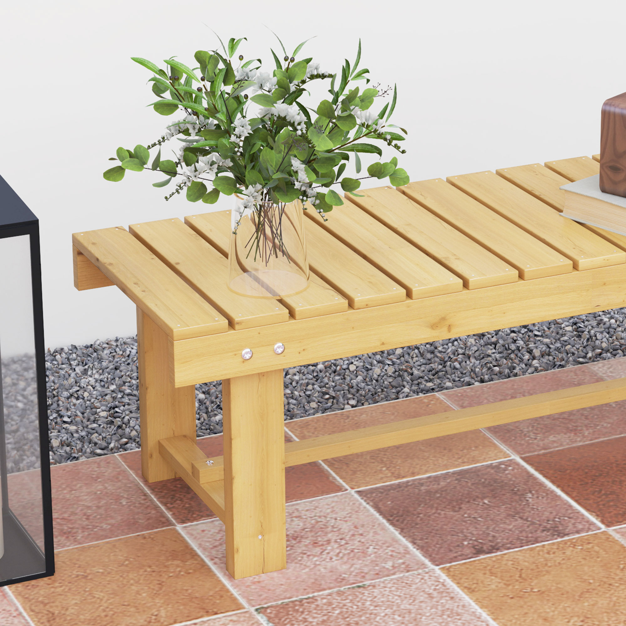 Panca in legno con un vaso di vetro con fiori sopra. La panca è su un patio piastrellato con ghiaia sul lato.