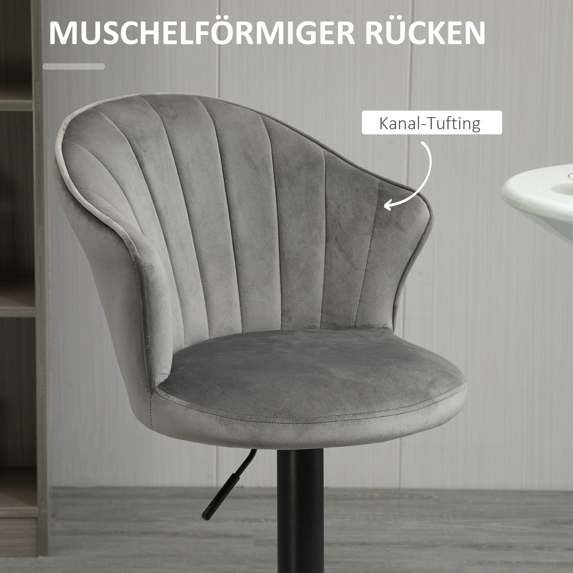 Grauer Samtstuhl mit muschelförmiger Rückenlehne, auf weiß-grauem Hintergrund.