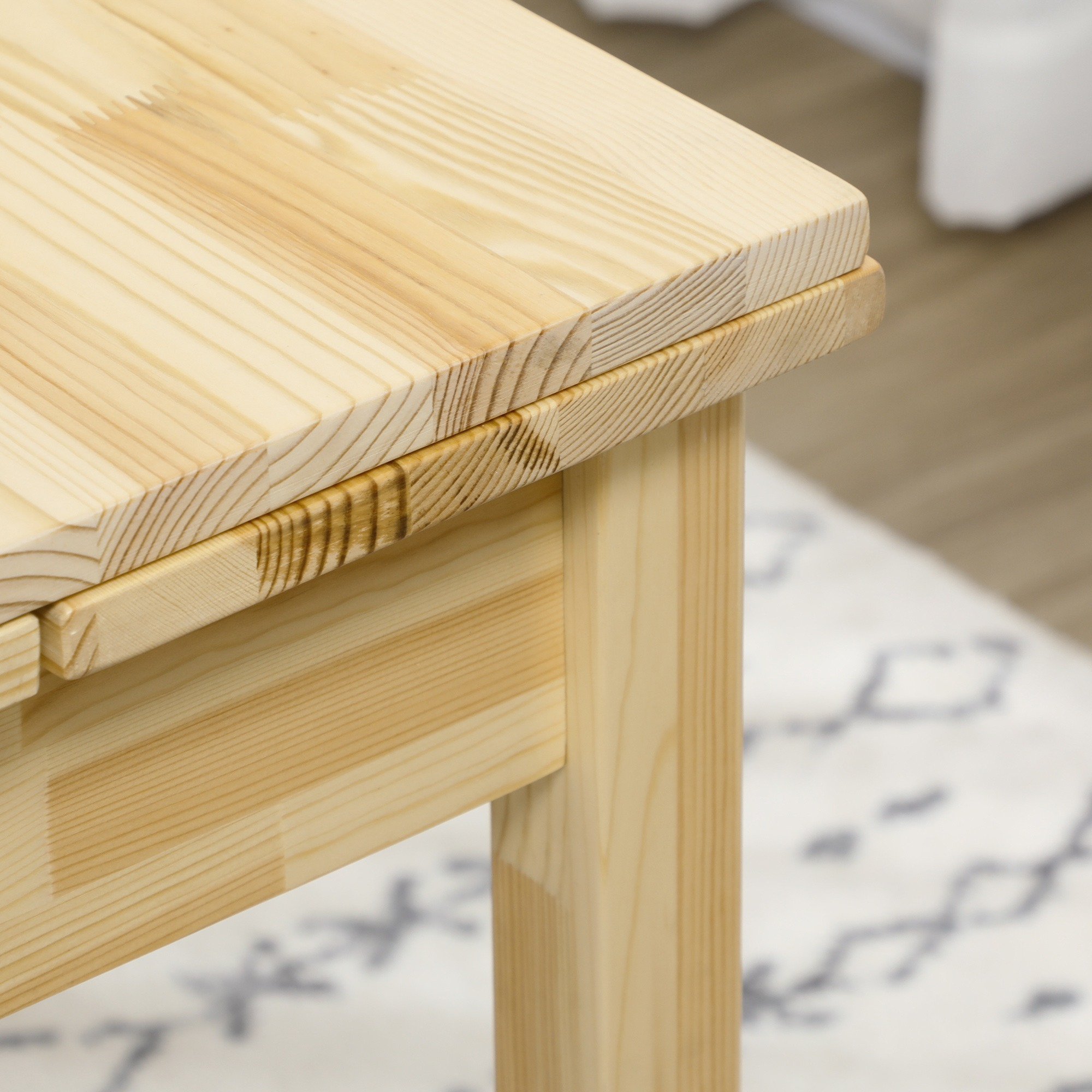 Nahaufnahme einer Holztischecke, die die Maserung zeigt. Der Tisch ist hell und hat eine quadratische Form.