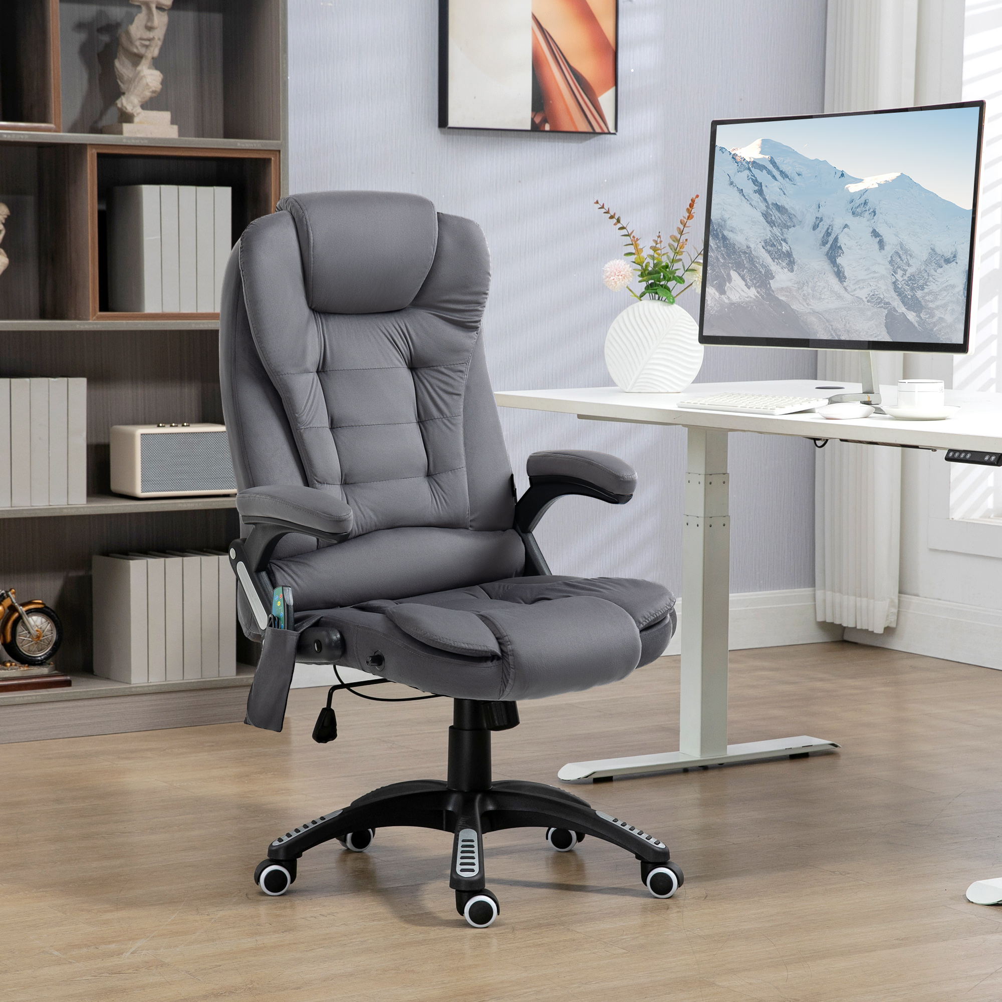 Grauer ergonomischer Bürostuhl in einem Raum mit Schreibtisch, Computer und Bücherregal.
