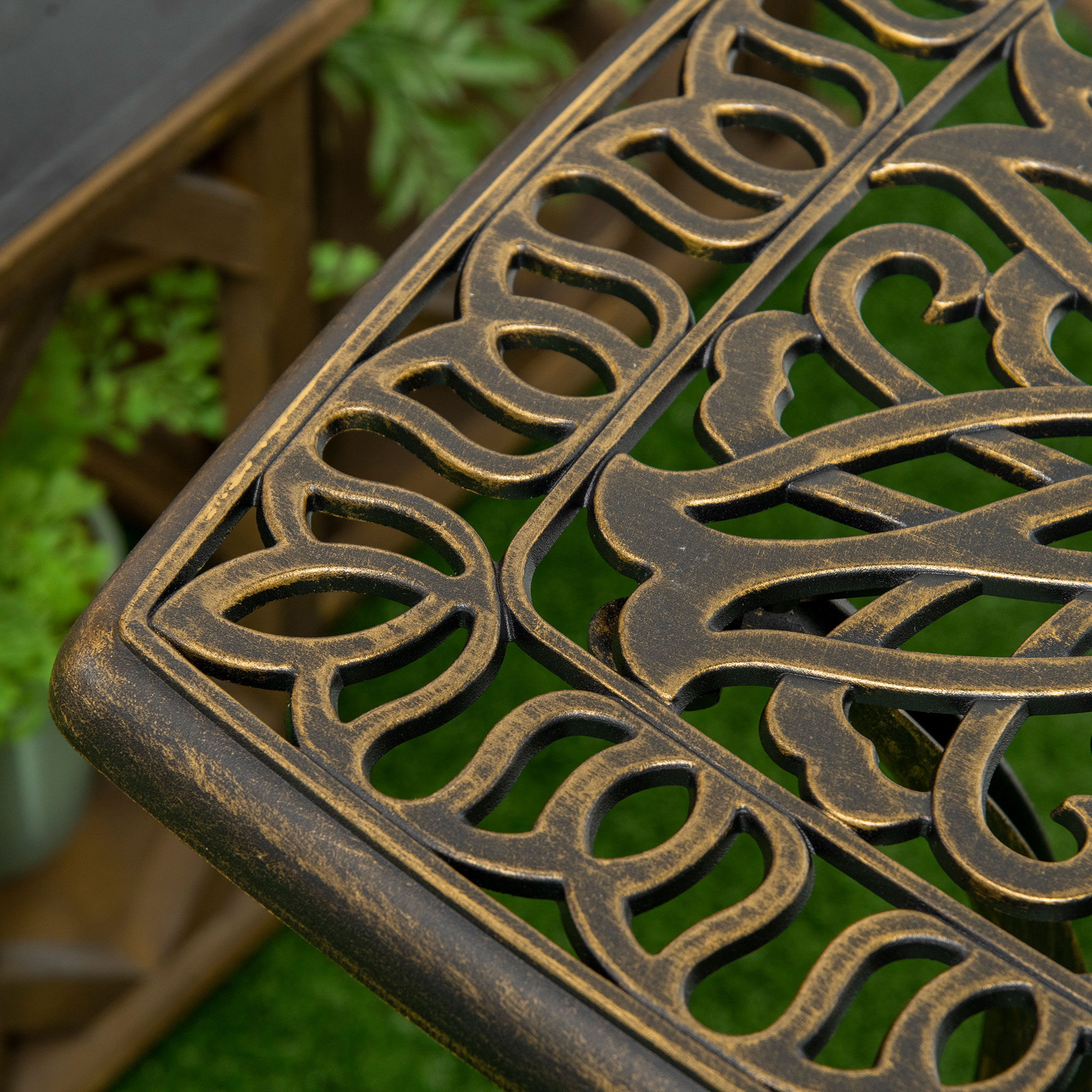 Nahaufnahme einer verzierten, bronzefarbenen Tischkante mit detaillierten floralen Mustern.