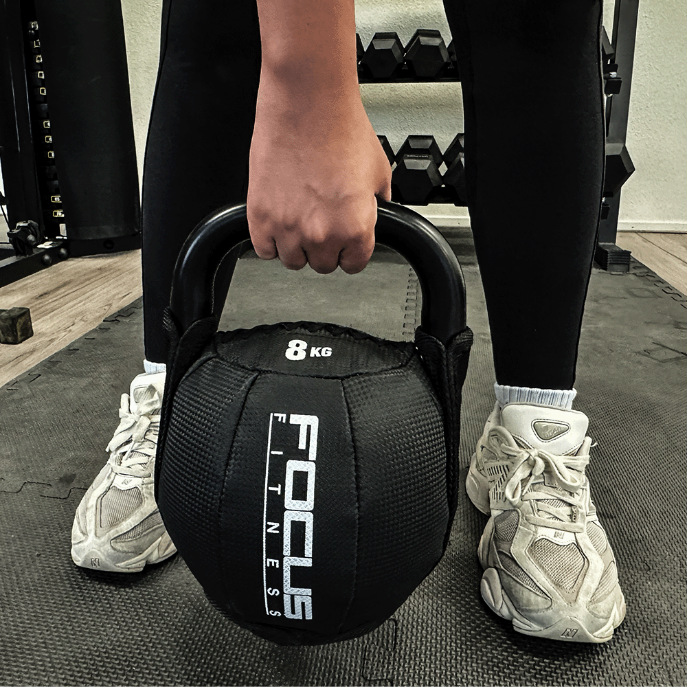 Person holding two black 3KG dumbbells. Focus Fitness logo visible. Wearing black clothes and a watch.