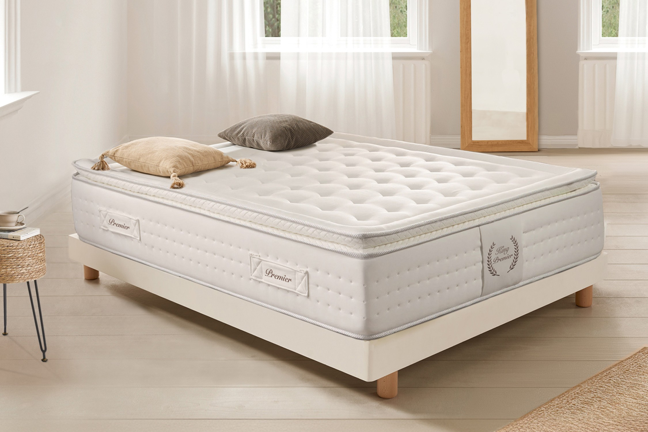Colchón en un marco de cama. Almohadas, lámpara y plantas. Colchón blanco con etiqueta Premier.