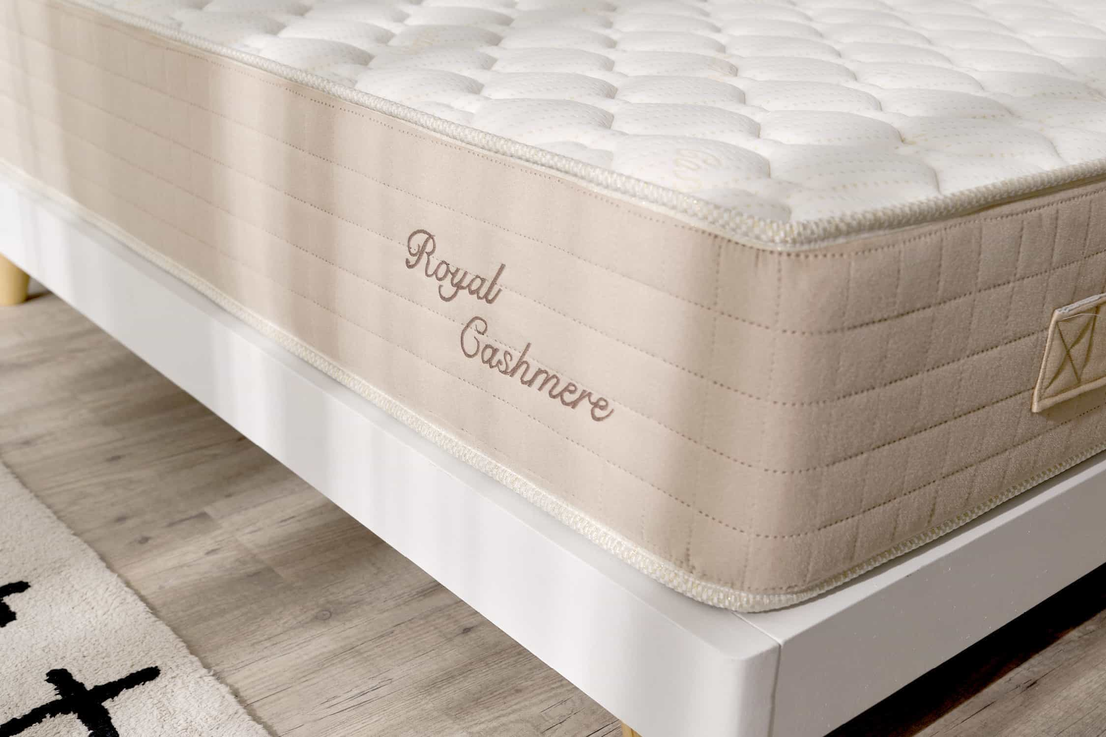 Primer plano de un colchón, lateral beige y parte superior blanca, la marca es Royal Cashmere.