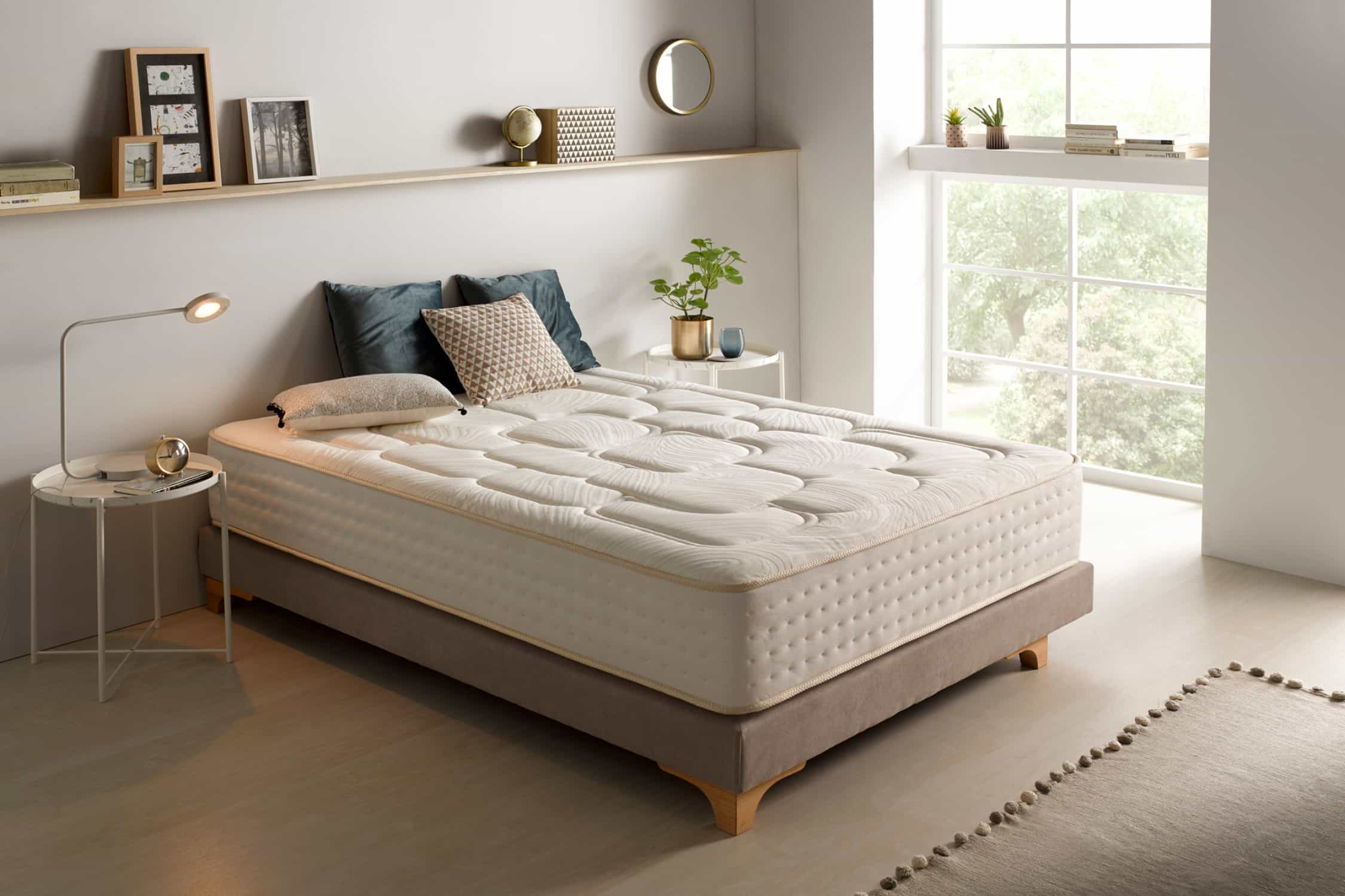 Un dormitorio con una cama y una ventana. La cama tiene un colchón, almohadas y una manta.