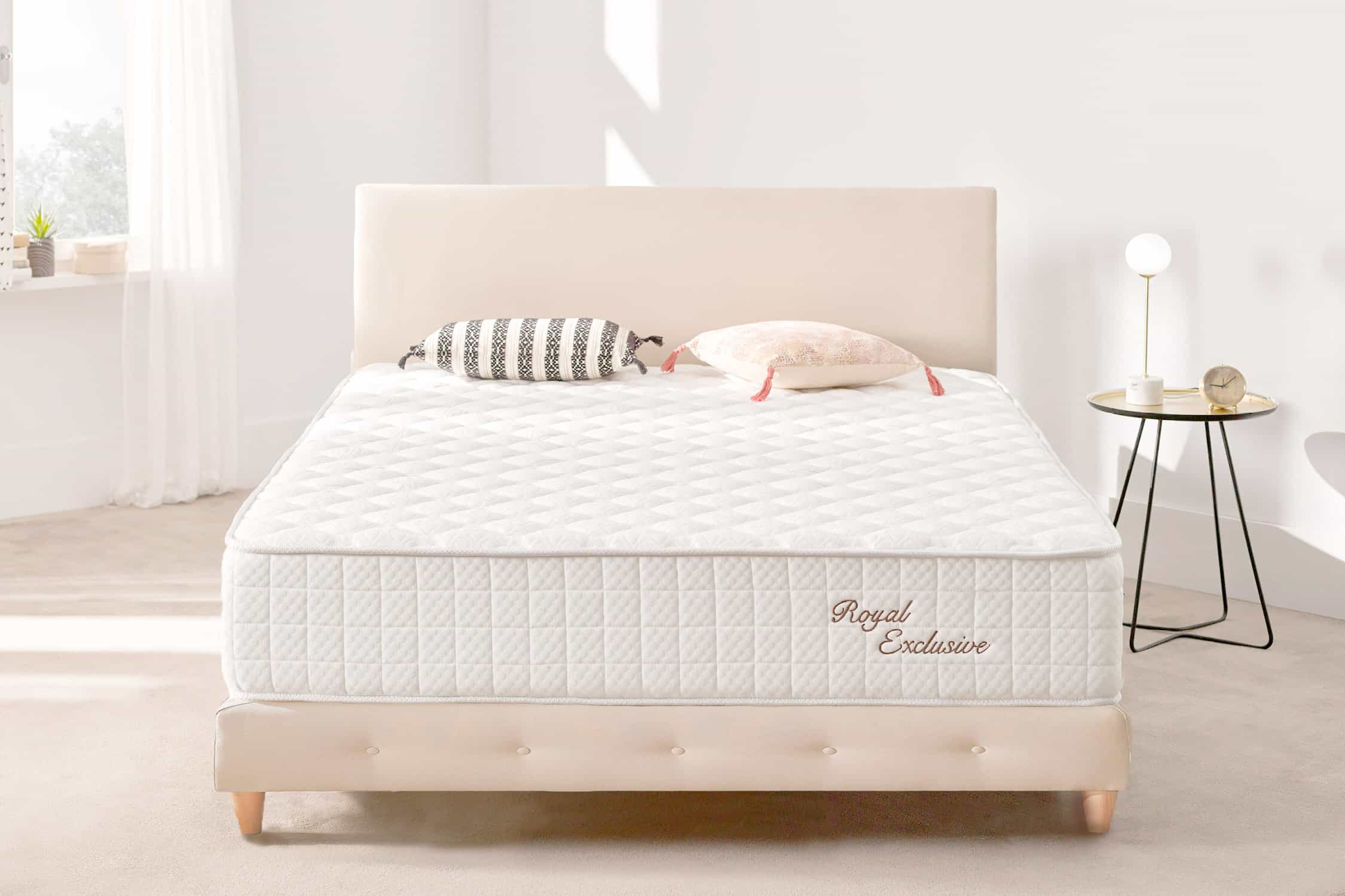 Dormitorio con cama, cabecero, almohadas y mesita auxiliar con lámpara.