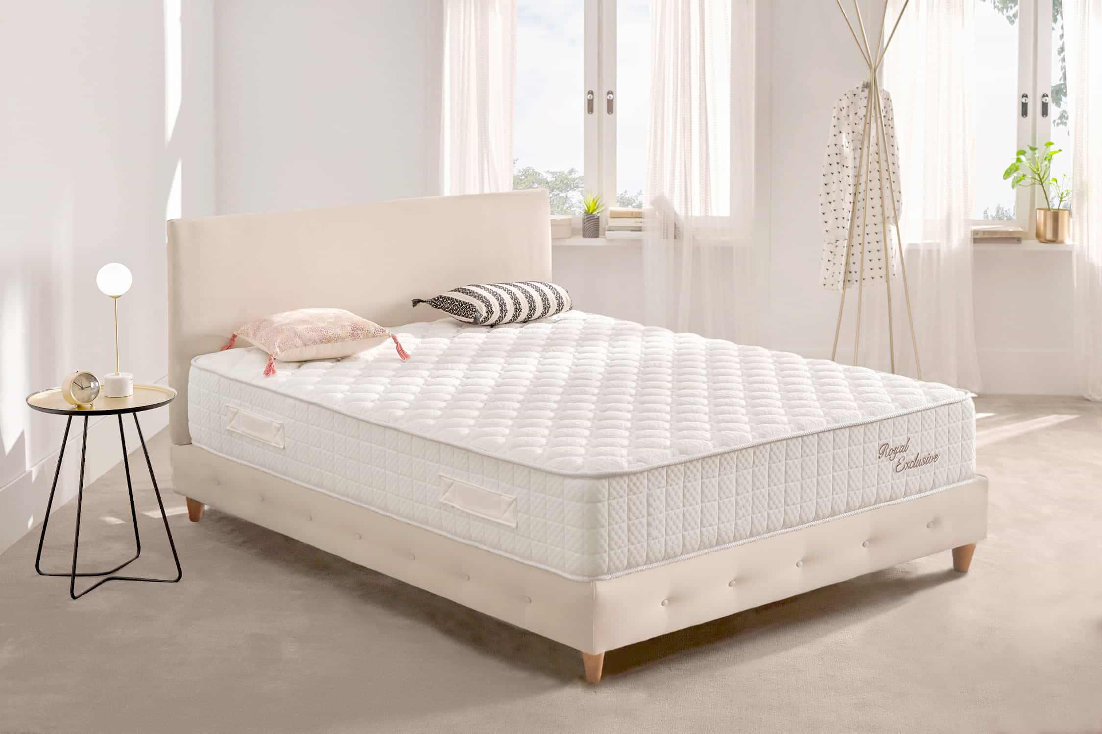 Dormitorio con cama, cabecero, almohadas y mesita auxiliar con lámpara.