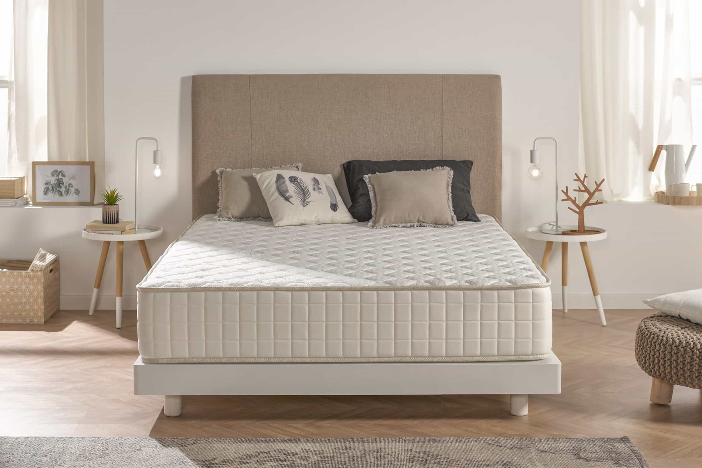 Dormitorio con cama, cabecero, lámparas y dos mesitas de noche. La cama tiene almohadas.