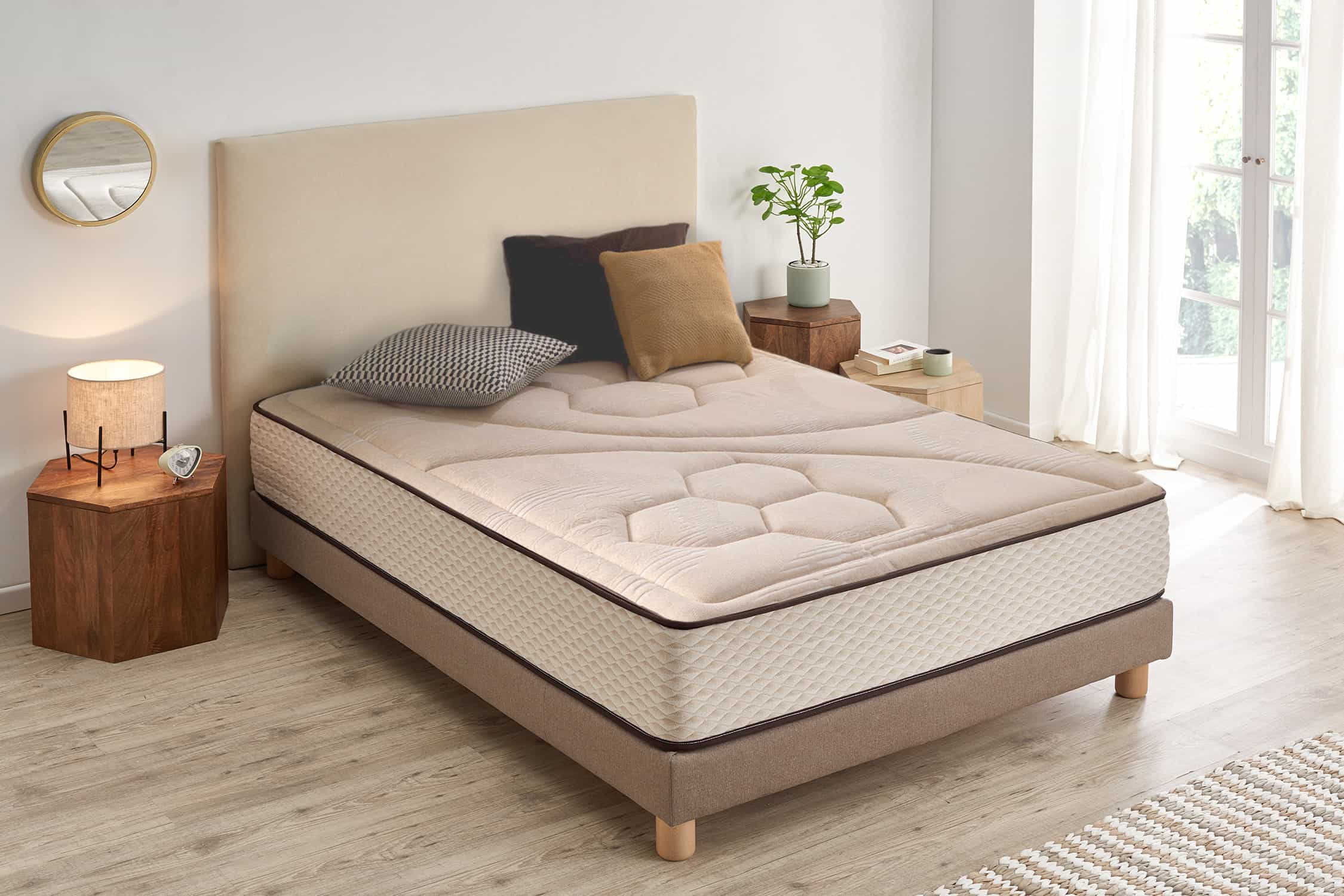 Dormitorio con cama, cabecero, almohadas y mesita de noche. La cama tiene un colchón beige.