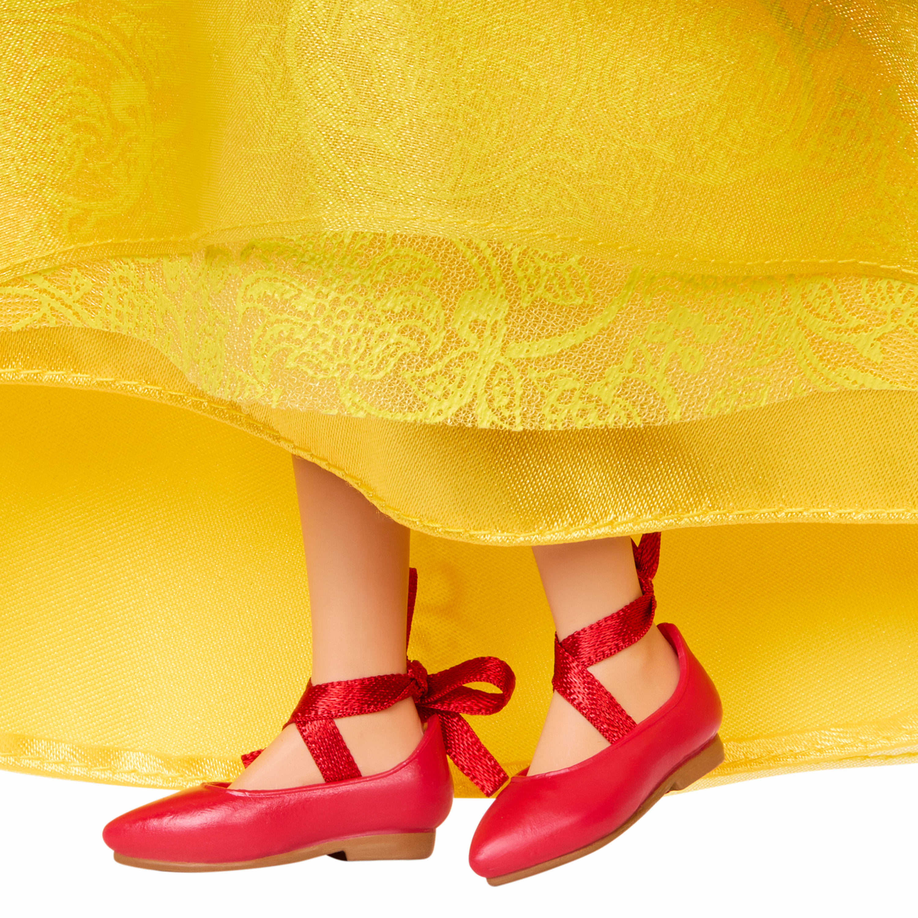 Puppenfüße in roten Schuhen mit Schleifen unter einem gelben Kleid.