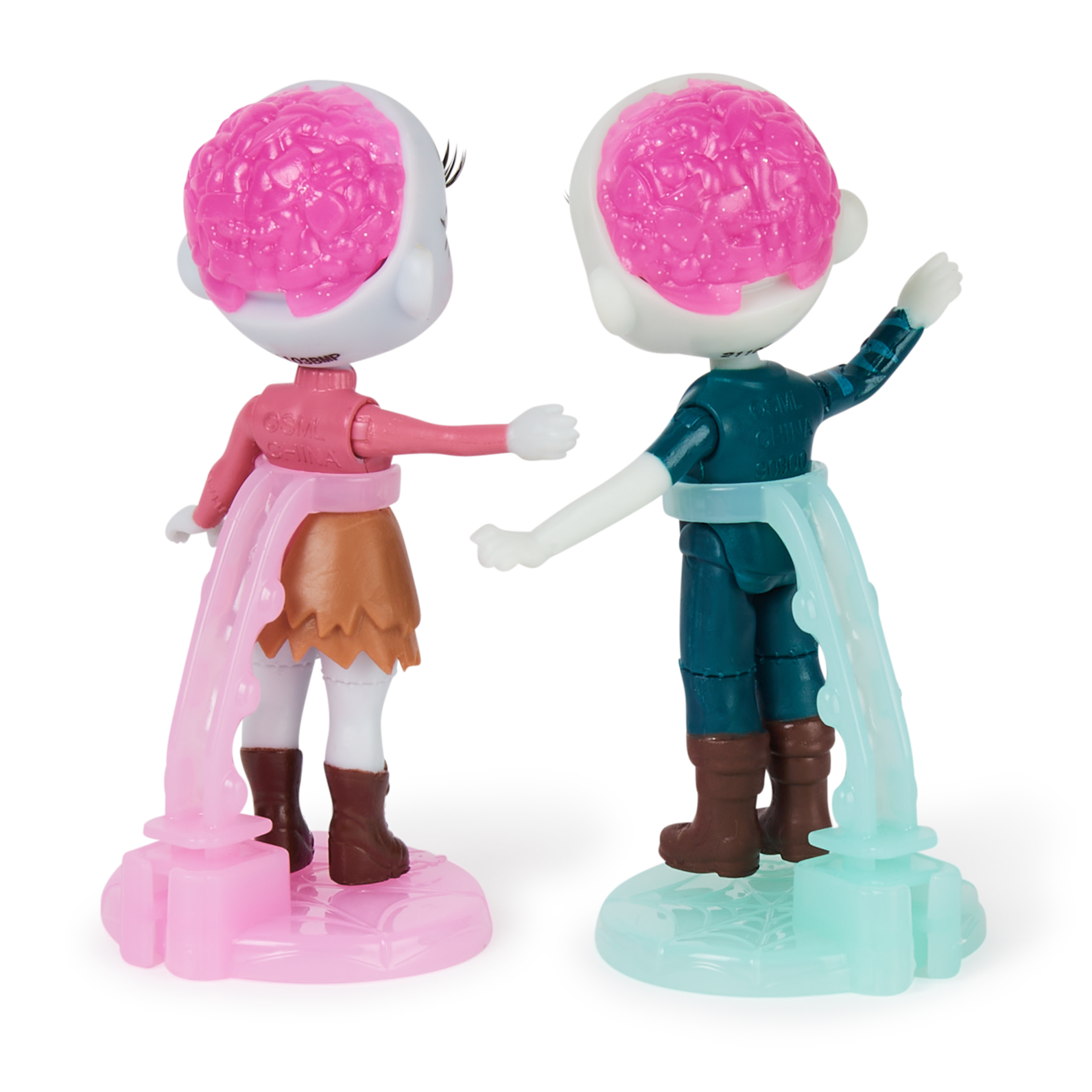 Dos muñecas tipo zombi con cerebros rosas expuestos. Están de pie sobre soportes y tienen rastros de colores que fluyen.