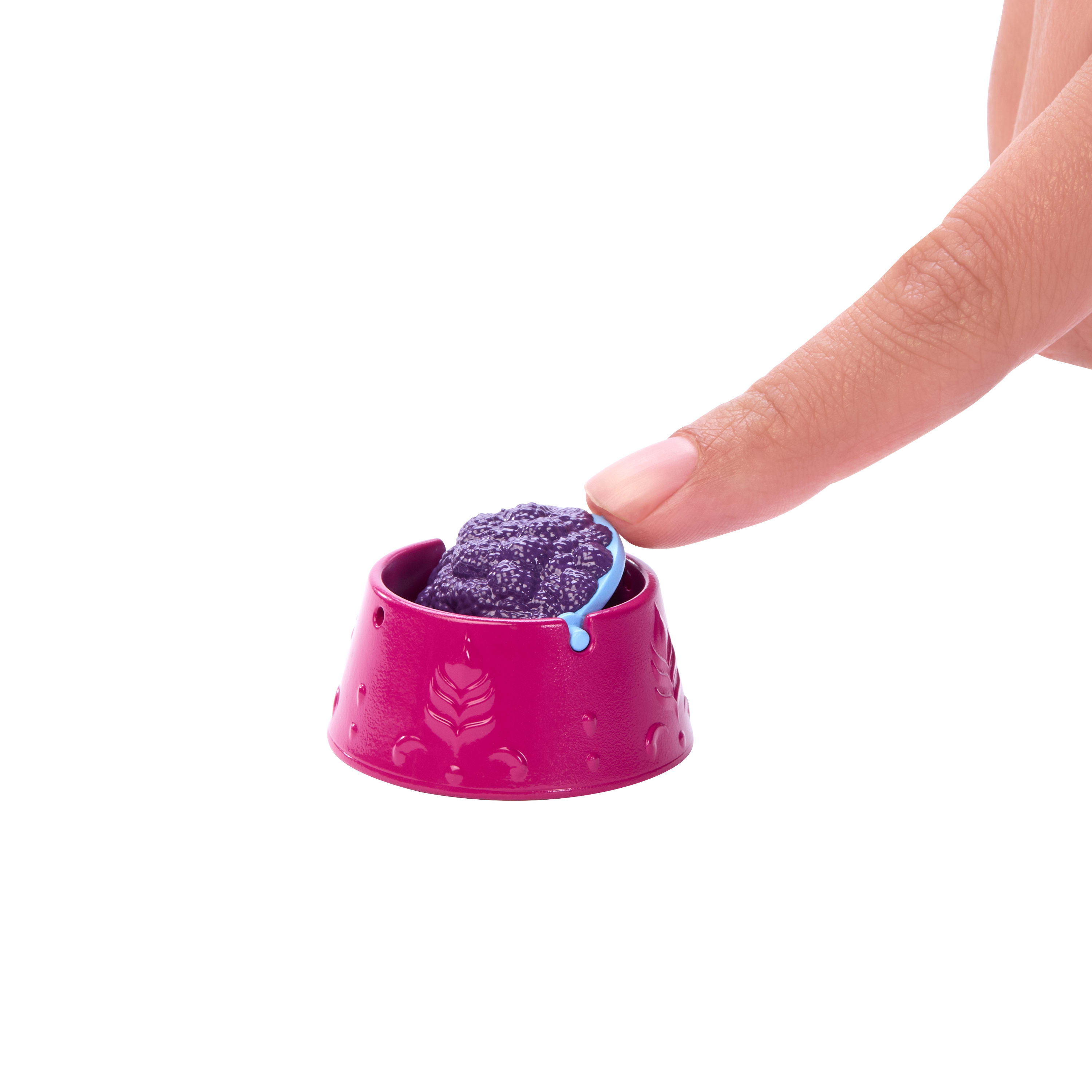Ręka dotyka różowej miski na jedzenie dla lalek. Miska ma fioletową substancję w środku.