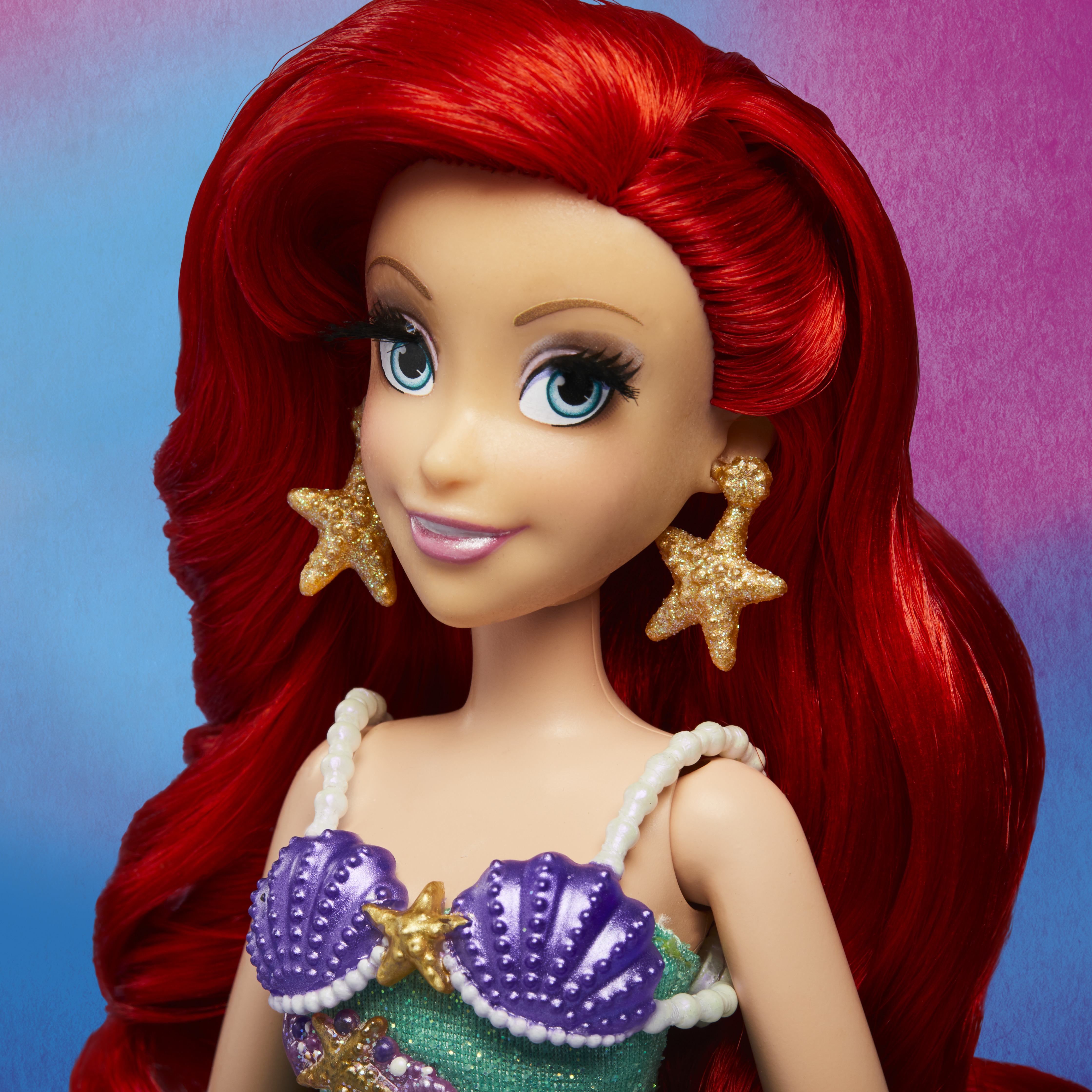 Ariel-Puppe mit roten Haaren, Sternohrringen und einem Muscheloberteil. Blauer und violetter Hintergrund.