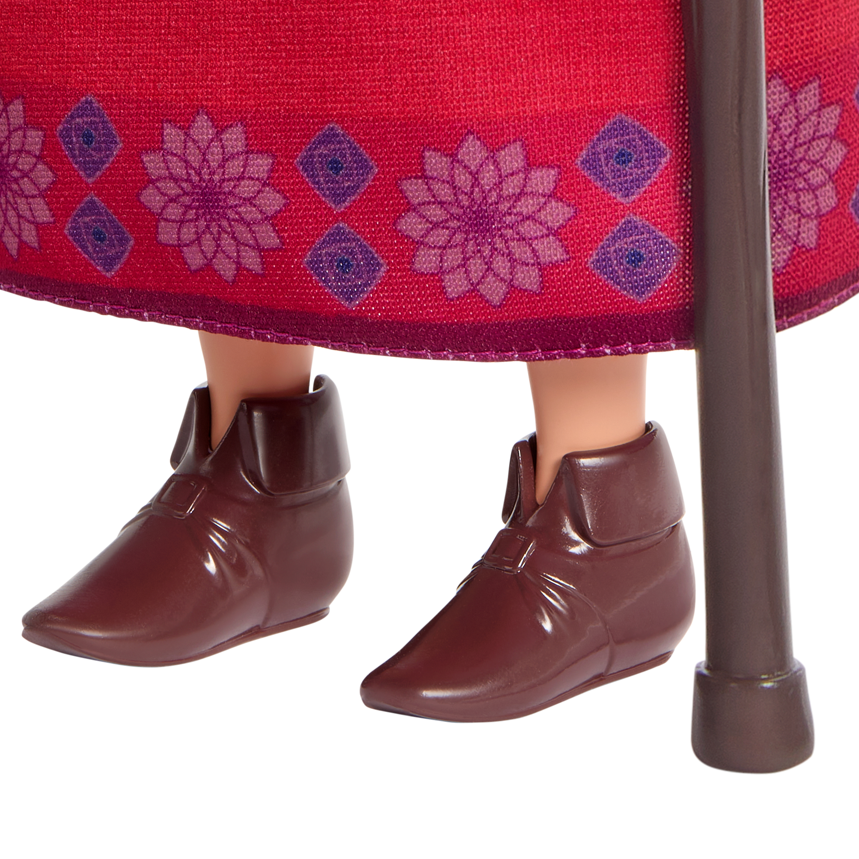 Zbliżenie stóp lalki w brązowych butach, stojących obok laski.