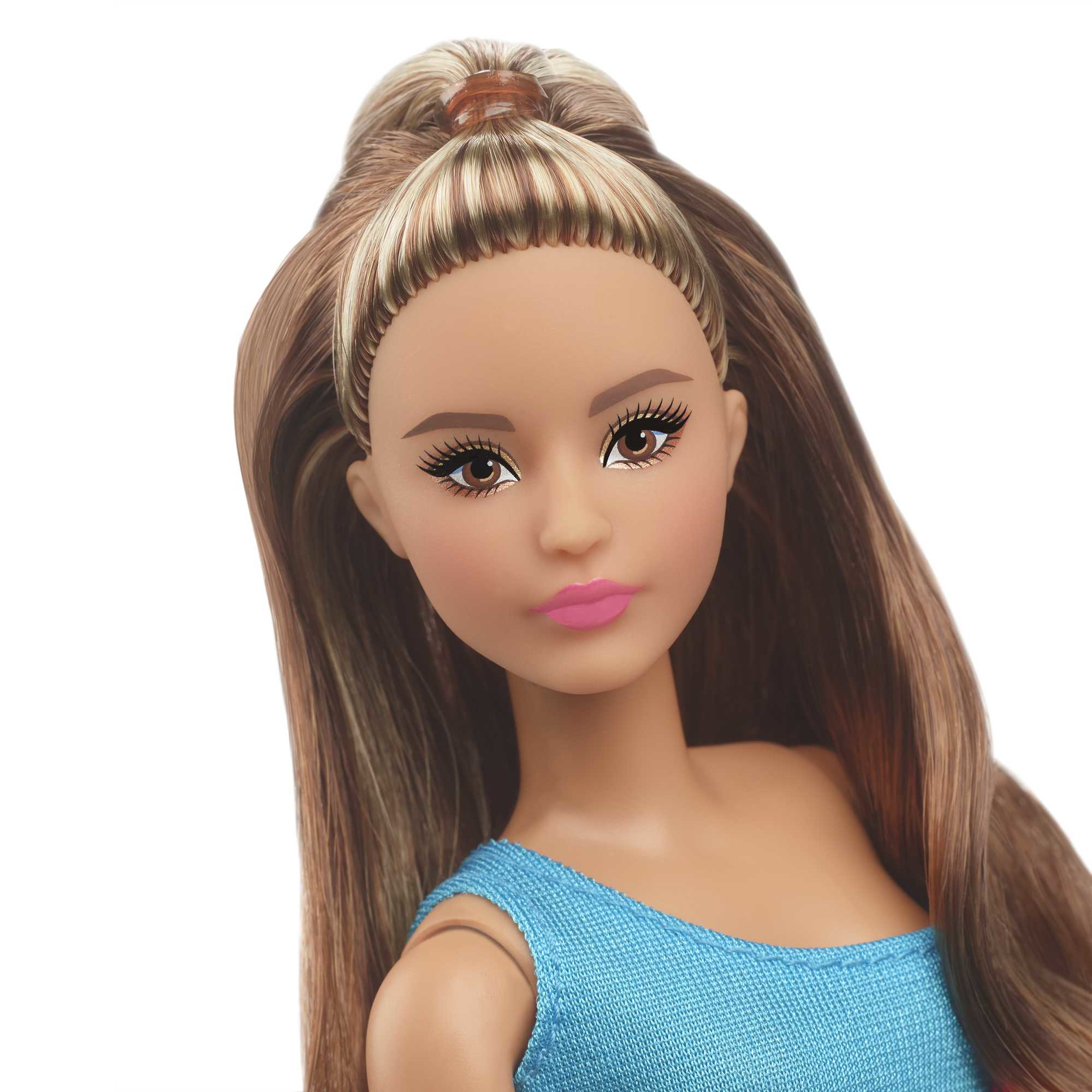 Nahaufnahme des Gesichts einer Puppe mit hohem Pferdeschwanz. Puppe hat braunes Haar mit blonden Highlights und rosa Lippen.