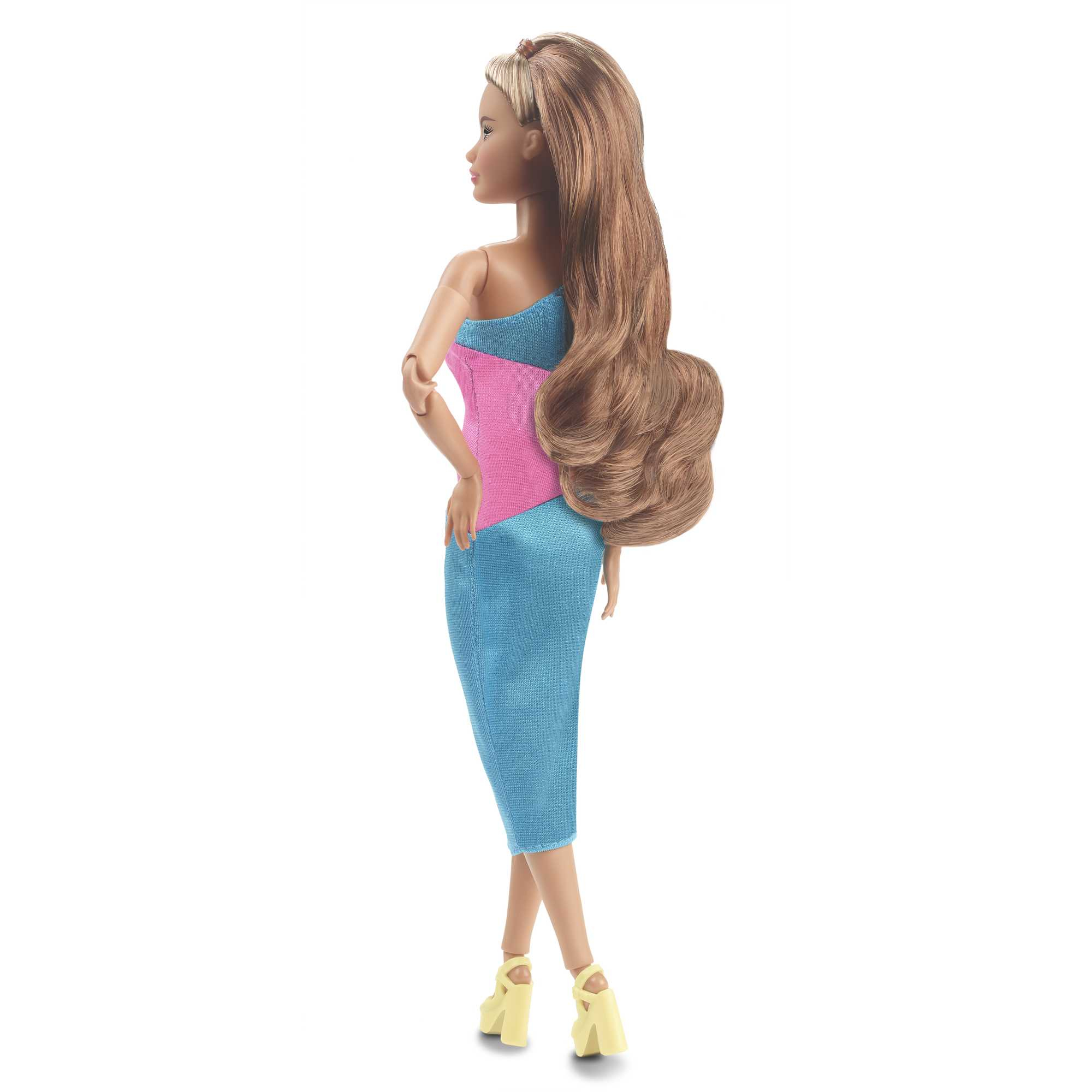 Puppe mit langen, welligen braunen Haaren, trägt ein blaues und rosa Kleid mit gelben Absätzen. Rückansicht.