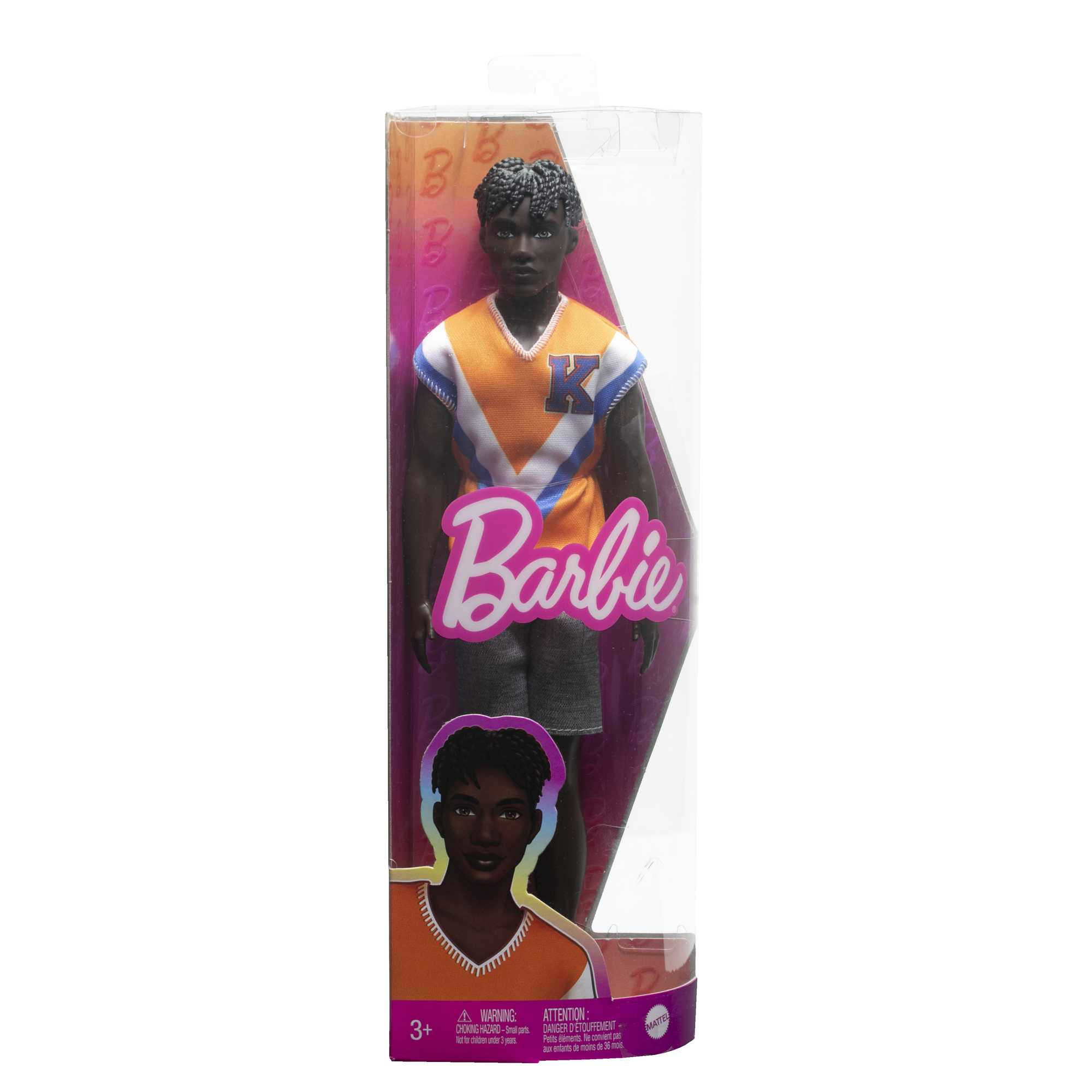 Schwarze Puppe in orange-blauem Oberteil, grauen Shorts, in einer durchsichtigen Box. Das Barbie-Logo ist sichtbar.