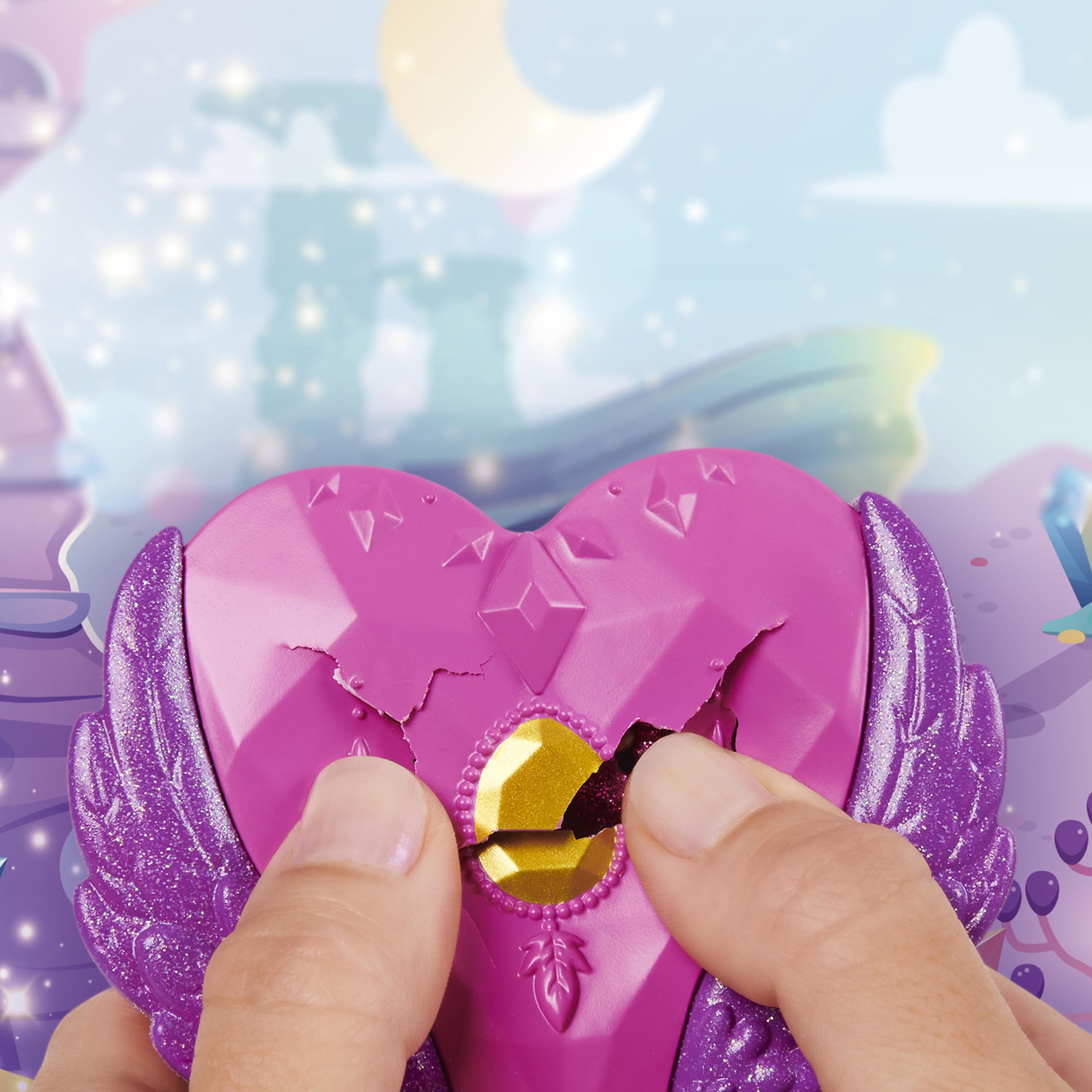 Manos rompiendo un juguete en forma de corazón. El juguete es rosa con alas, una joya dorada y acentos morados.