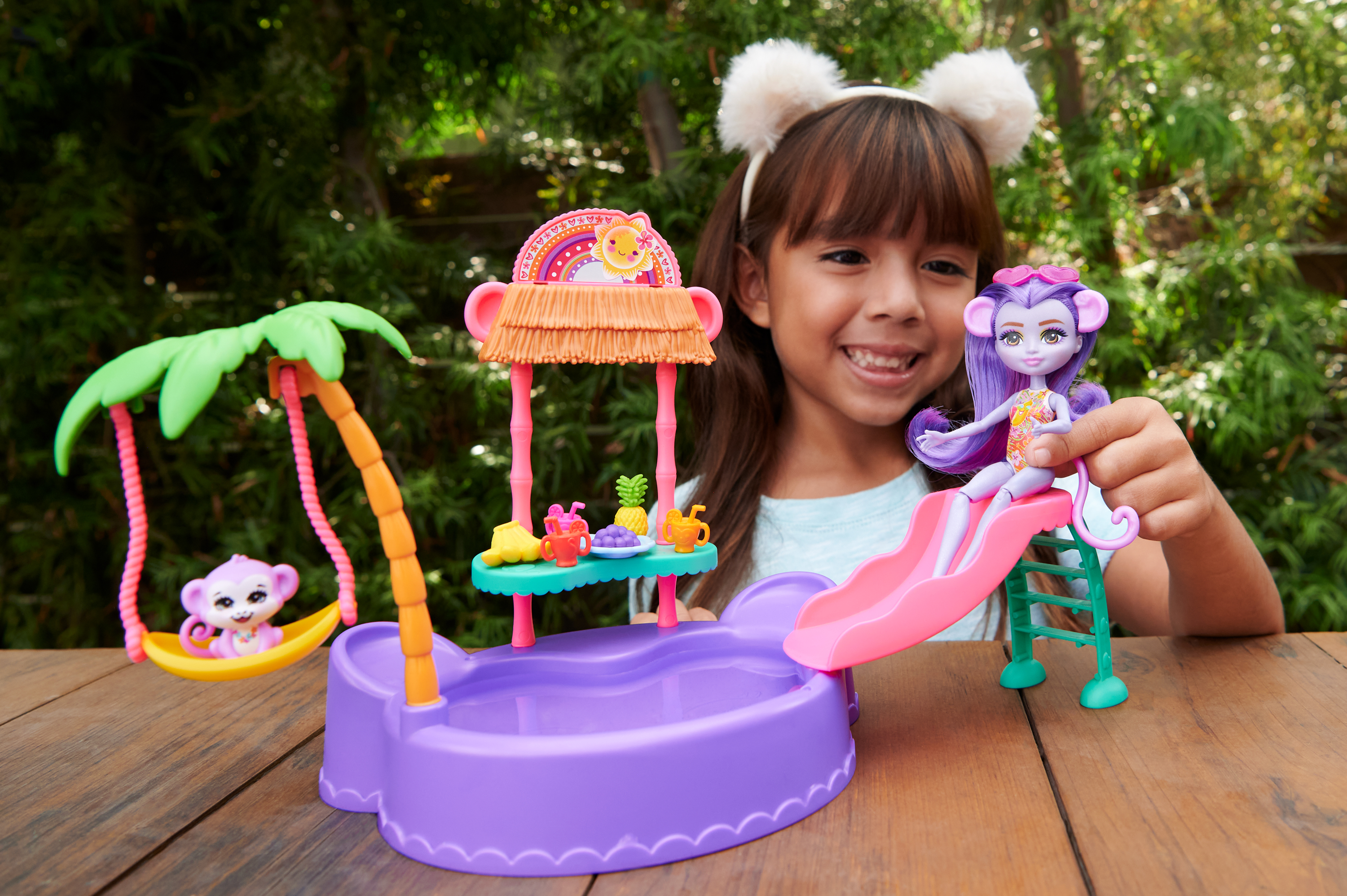 Una niña juega con un juego de juguetes con temática de monos, con un tobogán y un columpio.
