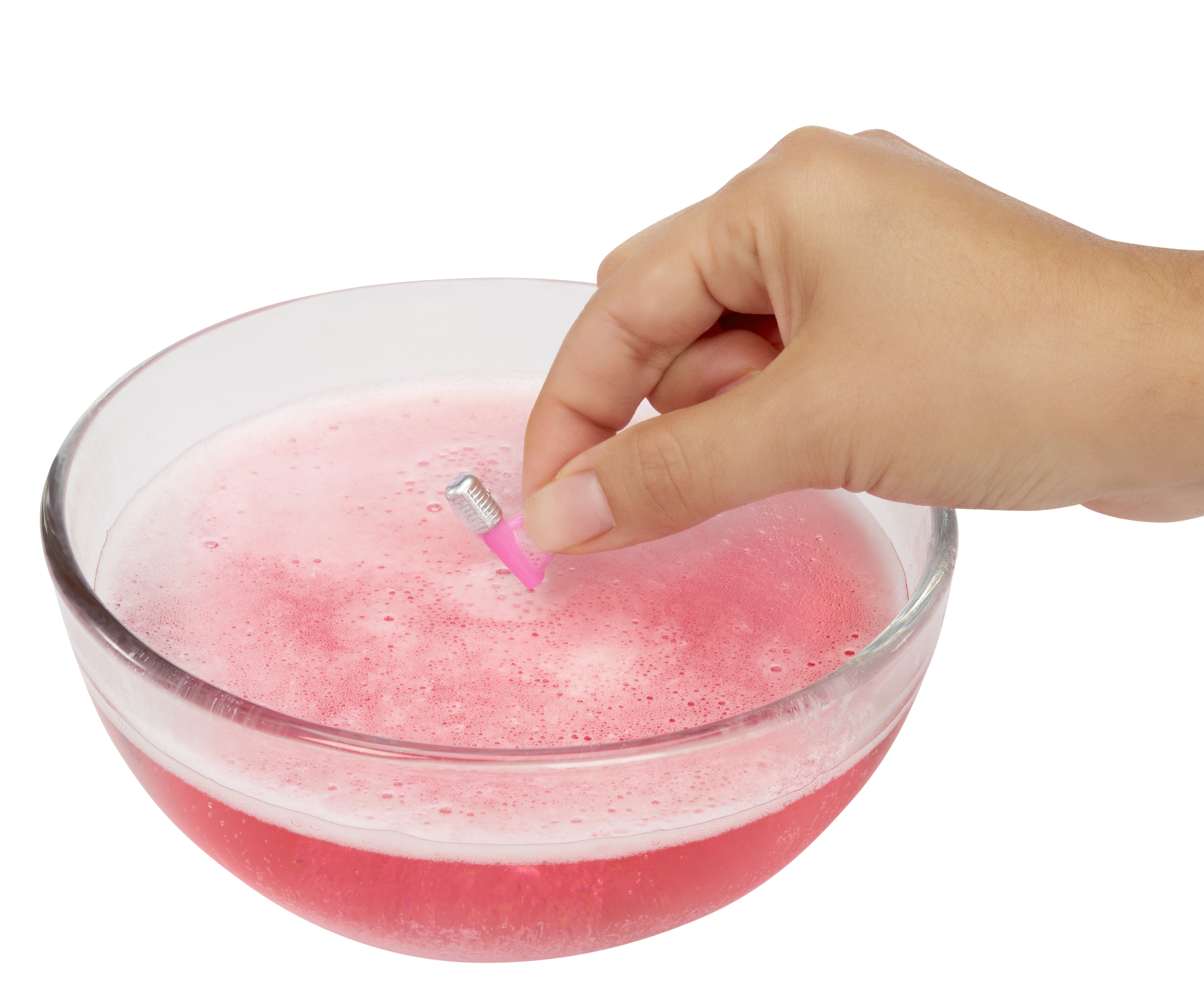 Dłoń trzymająca różowy przedmiot nad miską z różowym płynem. Płyn ma bąbelki.