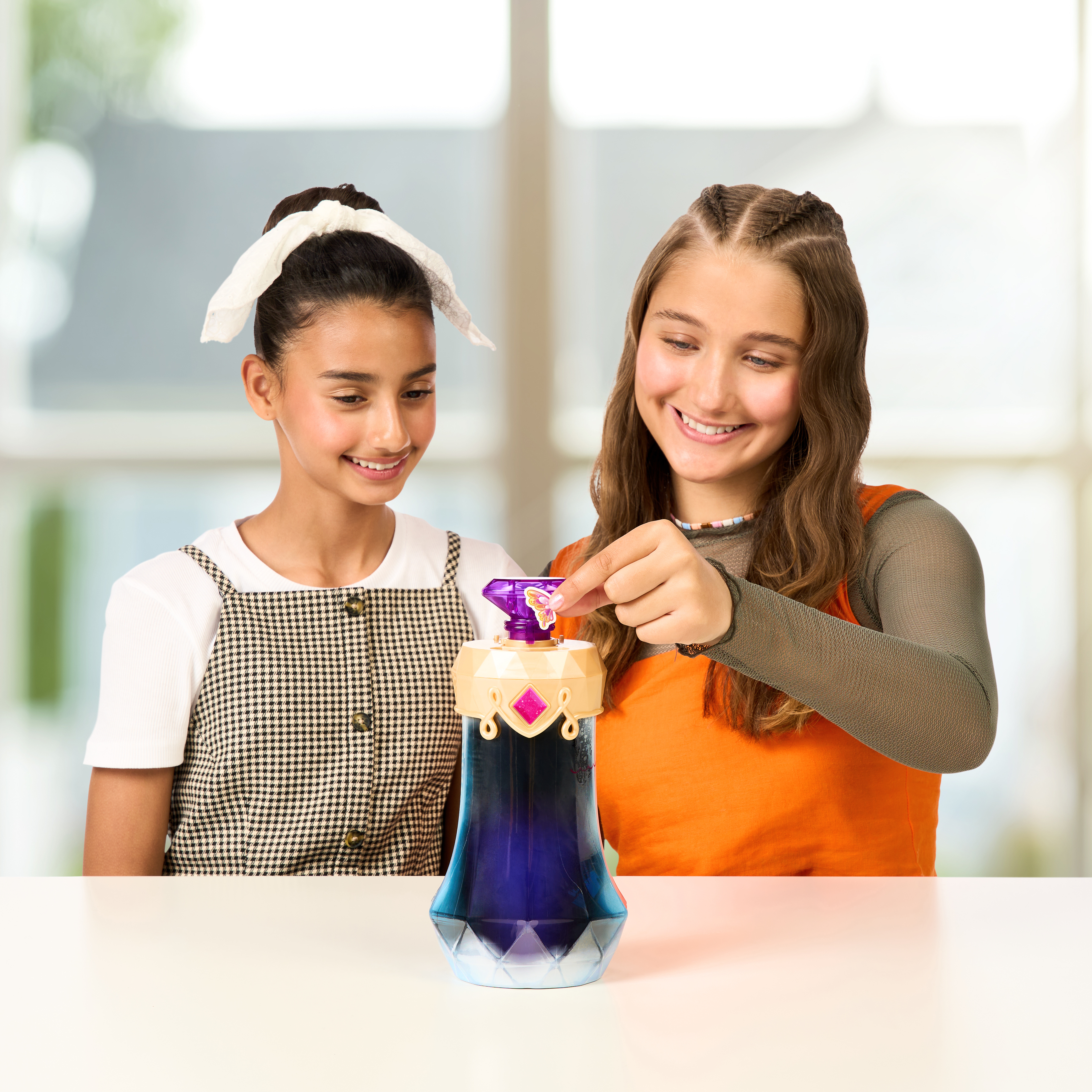 Dwie dziewczyny z zabawką, jedna trzyma klejnot, druga się uśmiecha. Zabawka jest niebieska z klejnotem.