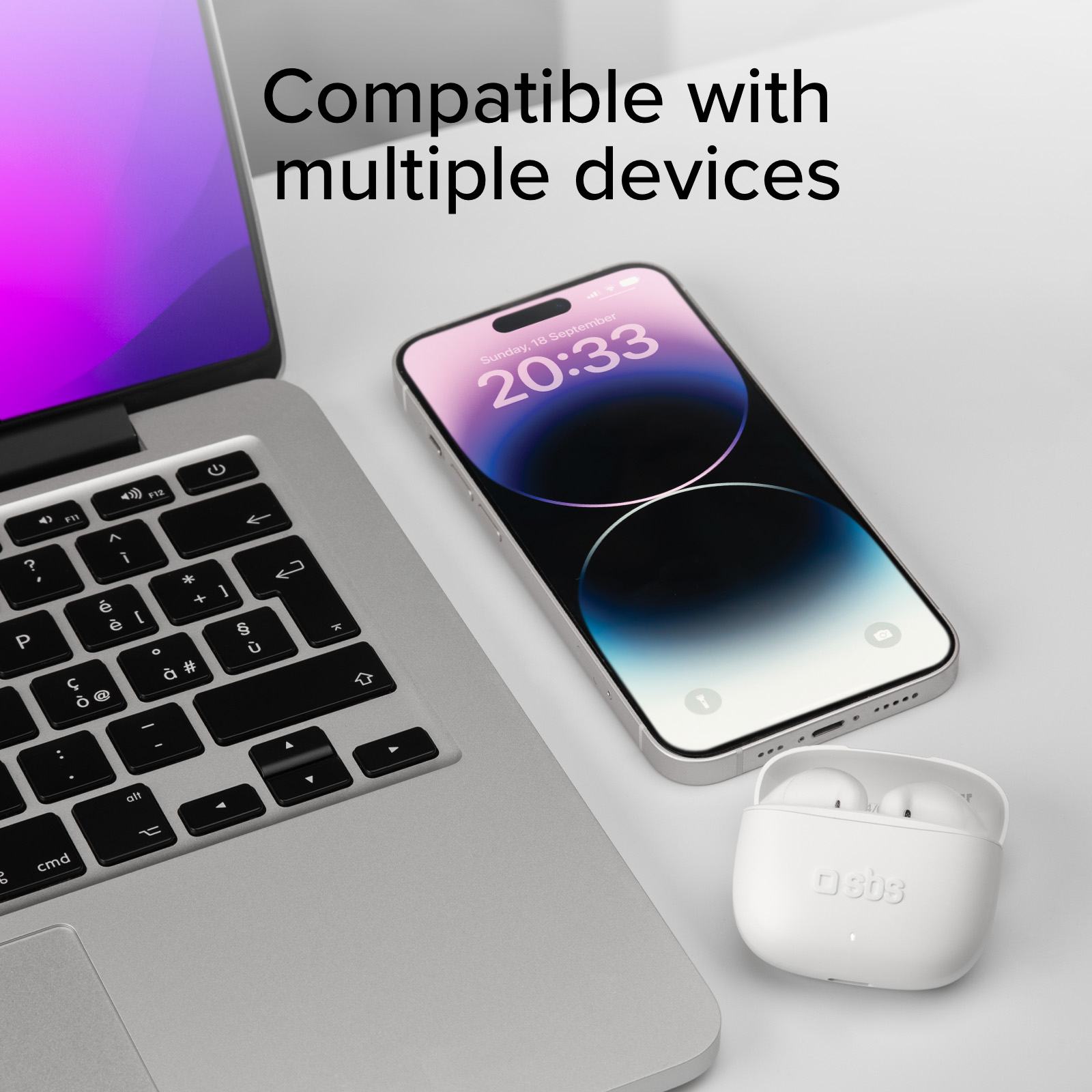 Białe słuchawki, telefon i laptop na stole. Ekran telefonu pokazuje zegar.