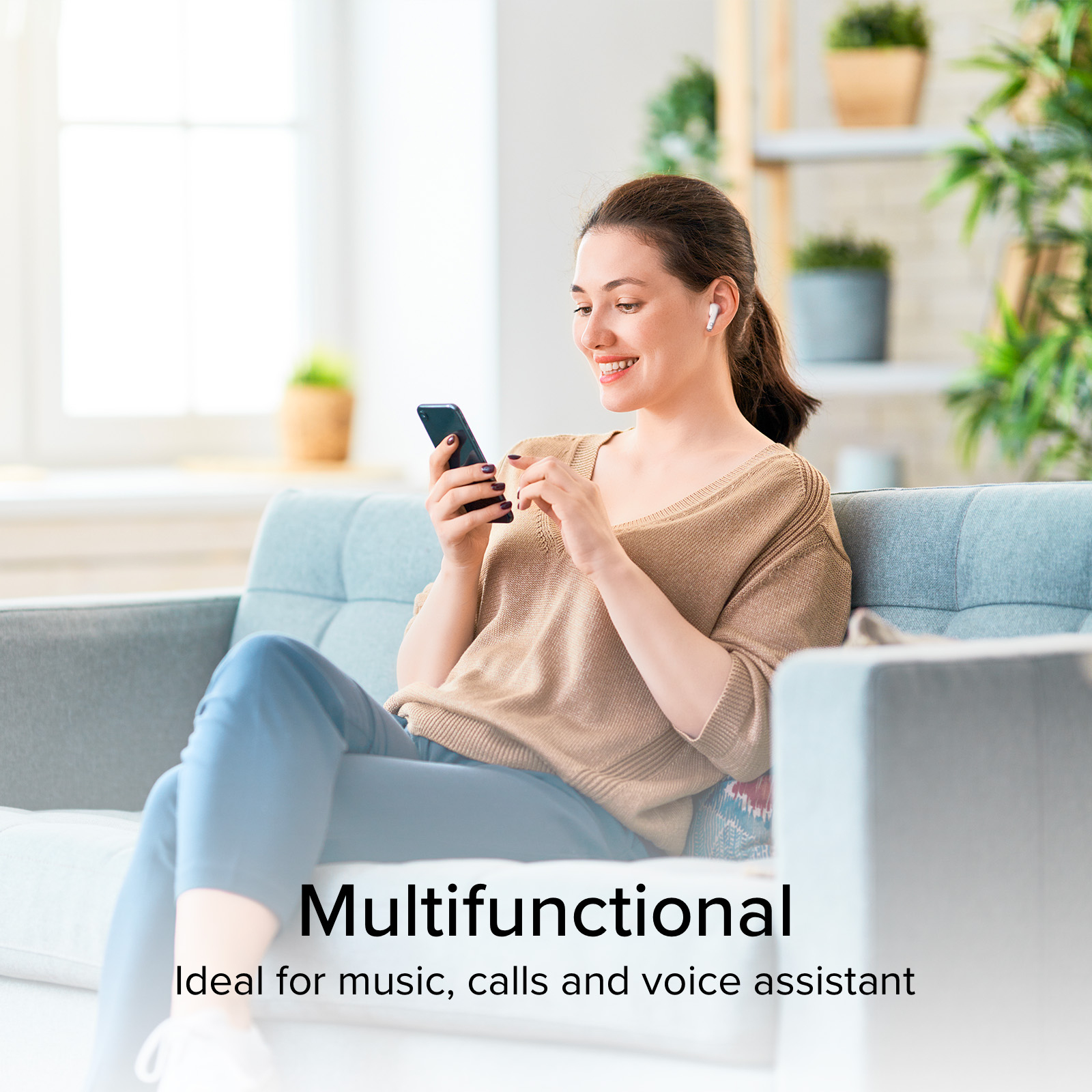 Kobieta na sofie używa telefonu, z słuchawkami. Tło: półka z roślinami.