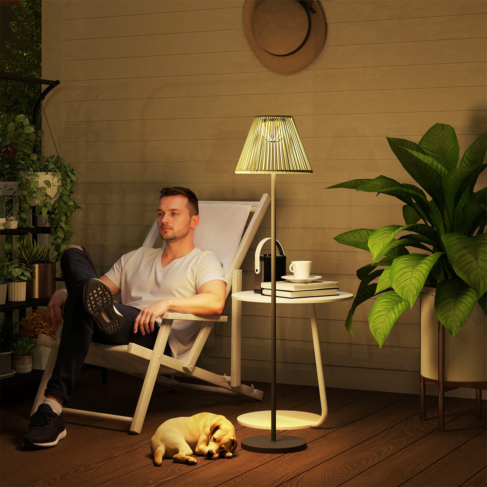 Ein Mann sitzt in einem Stuhl auf einer Holzterrasse mit einer Lampe, einem Hund und Pflanzen. Abendliche Szene.