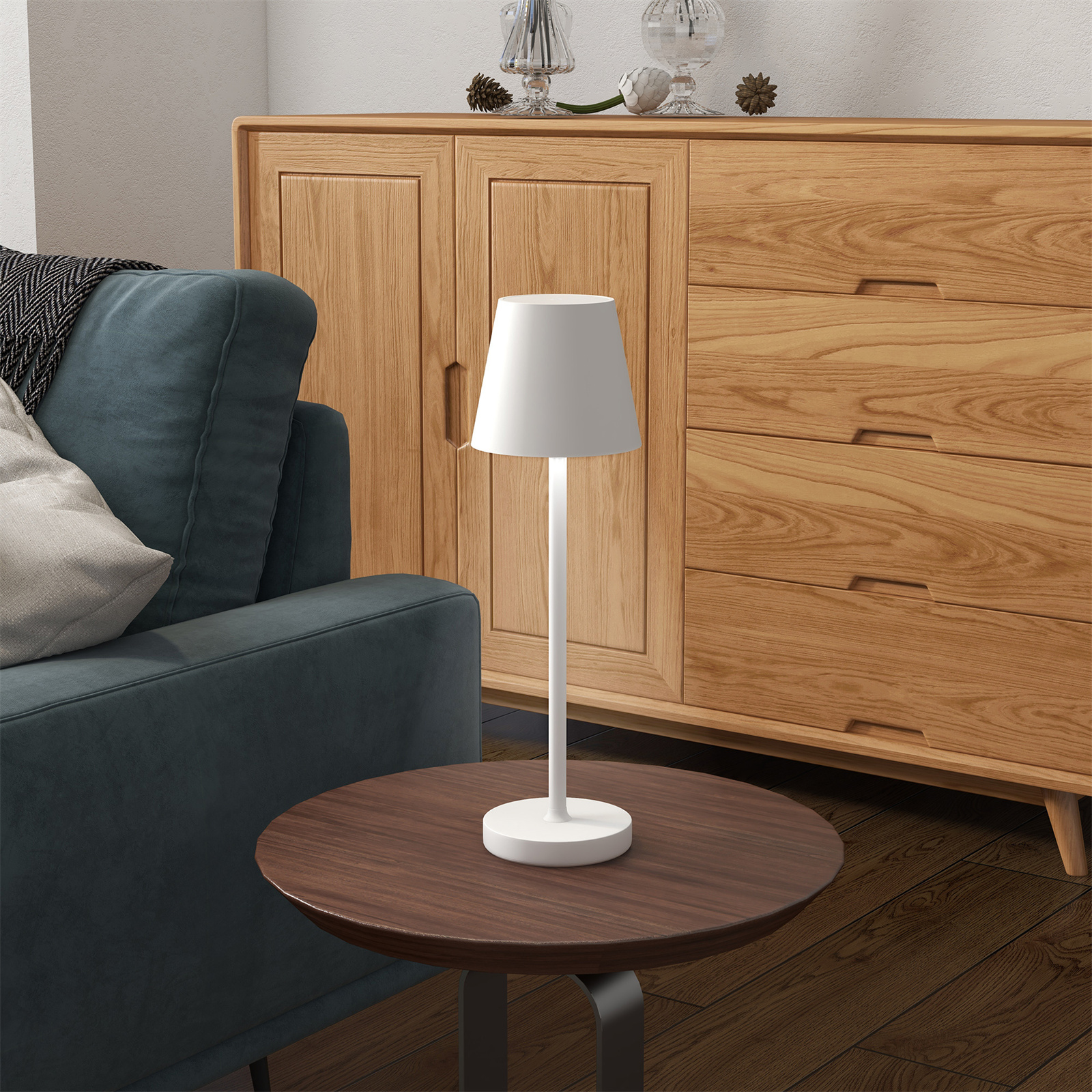 Weiße Lampe auf Holztisch, neben türkisfarbenem Sofa und Holzschrank im Hintergrund.