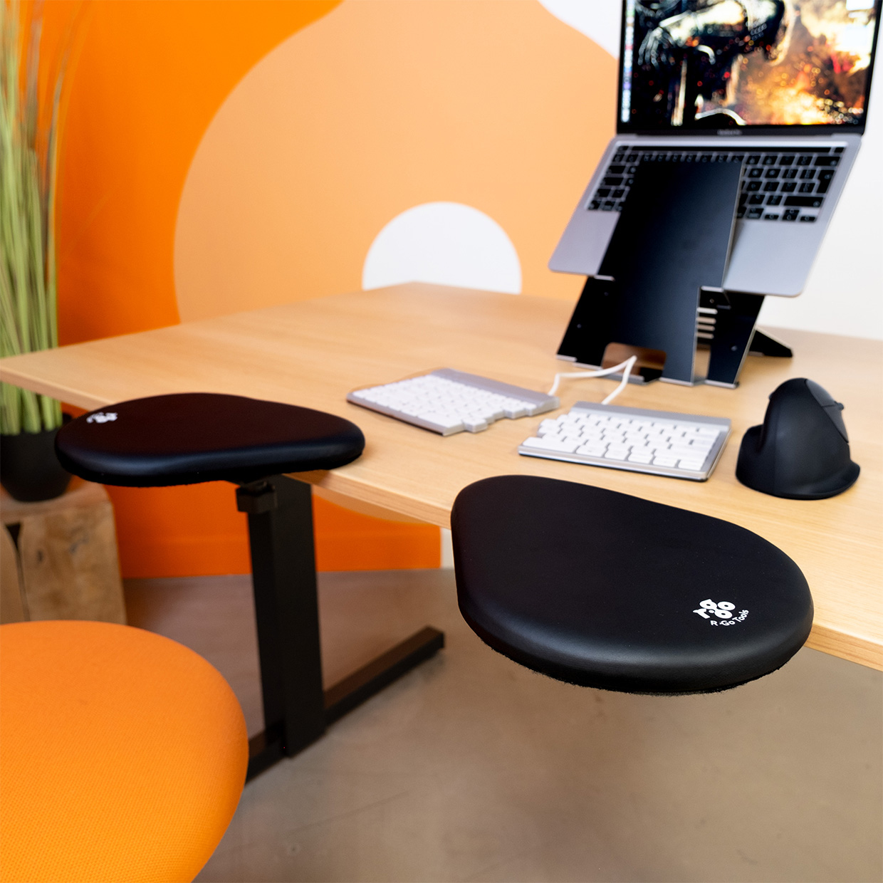 Bureau avec deux coussins noirs et un ordinateur portable. Un clavier blanc sur le bureau.