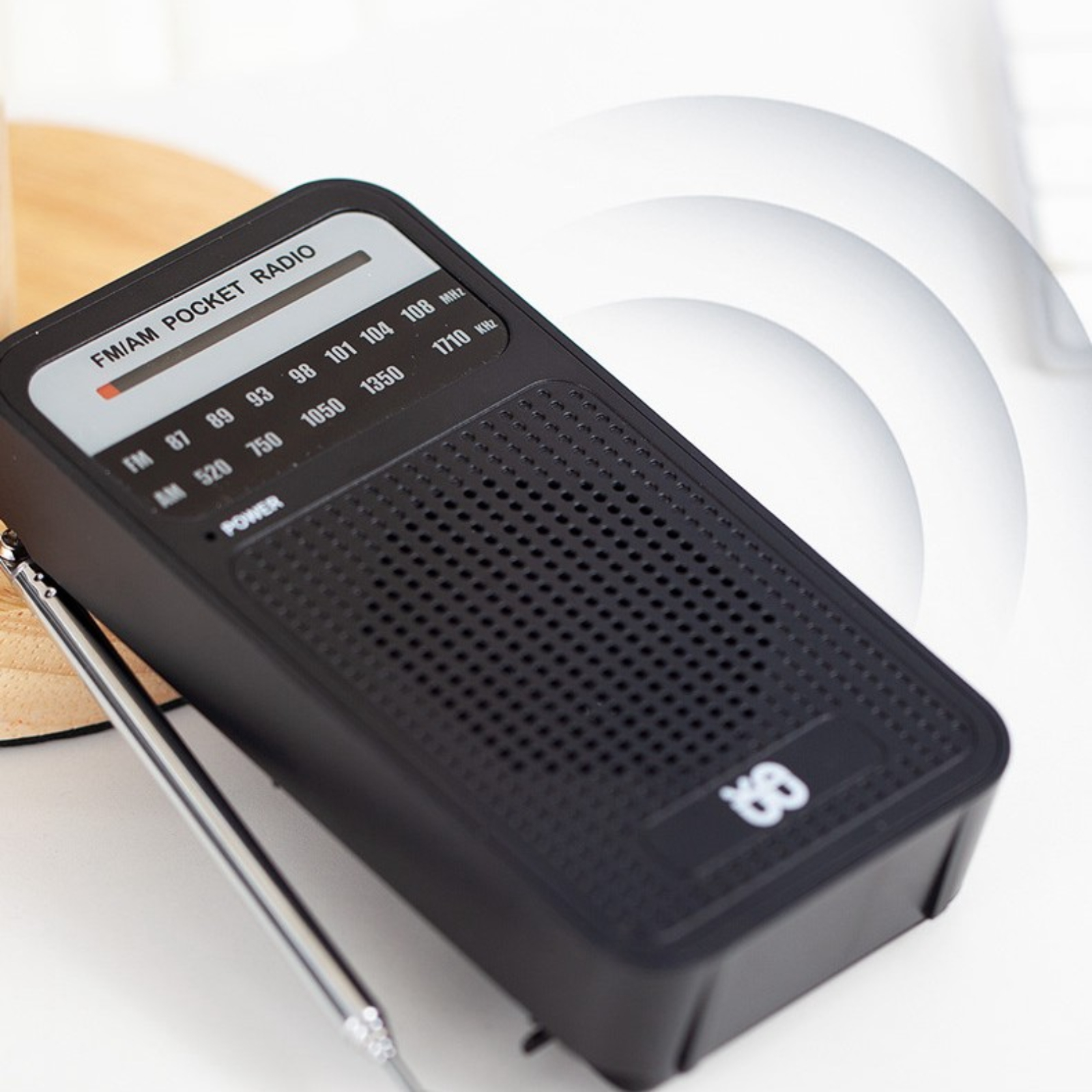 Ein schwarzes Taschenradio mit Antenne und Lautsprecher, mit einem Kabel, das an die Kopfhörerbuchse angeschlossen ist.