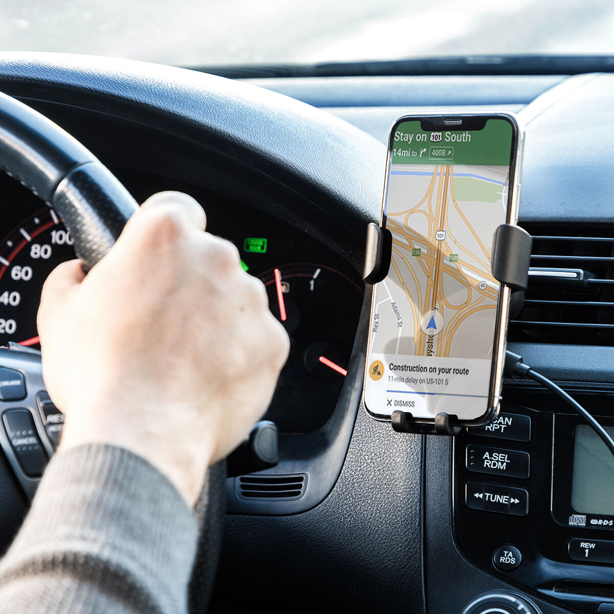 Una persona tiene in mano un telefono con un'app di navigazione in auto. Il telefono è in un supporto.