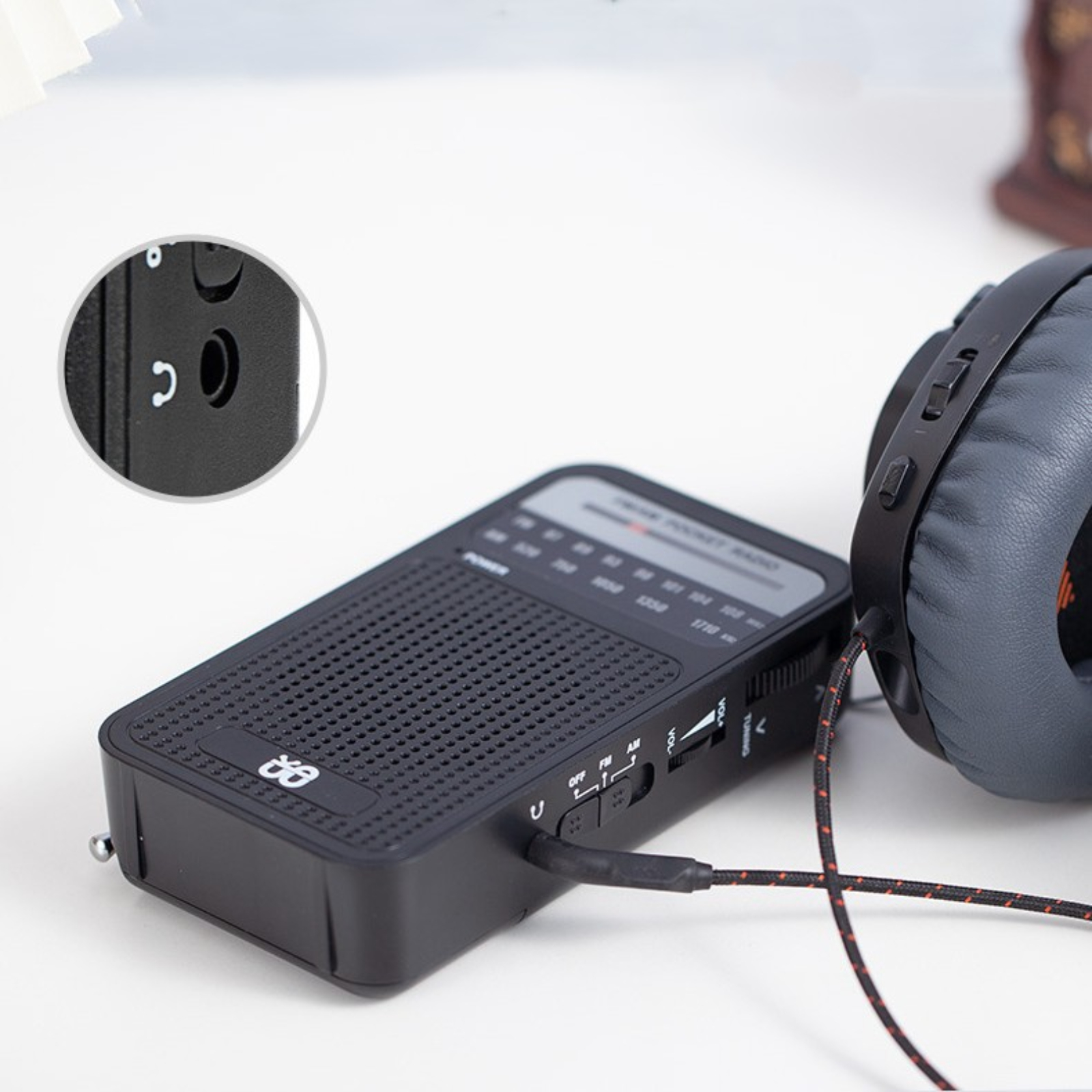 Ein schwarzes Taschenradio mit Antenne und Lautsprecher, mit Kopfhöreranschluss und Kopfhörer.