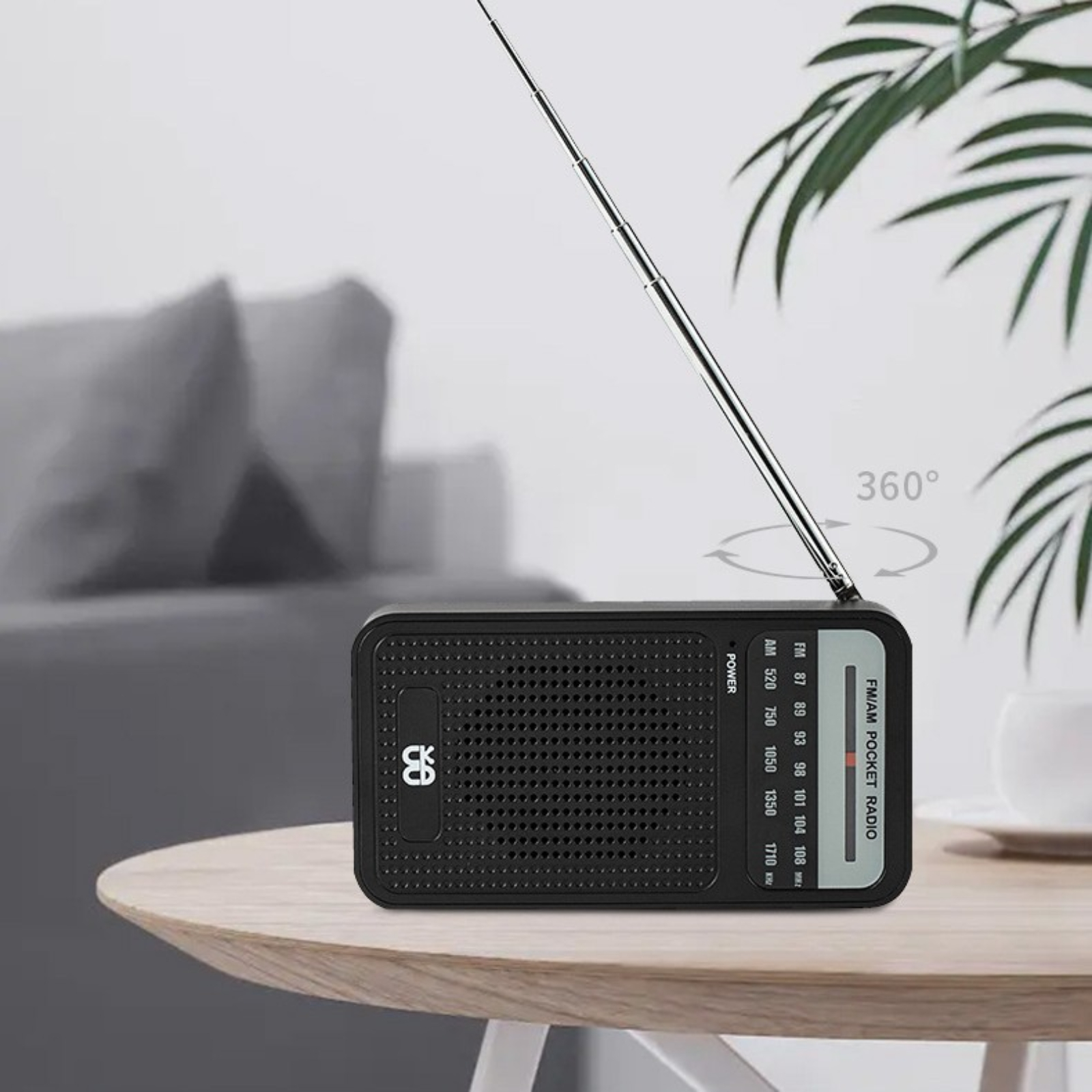 Schwarzes Taschenradio auf einem Tisch. Die Antenne ist hochgeklappt. Die Oberfläche ist Holz.