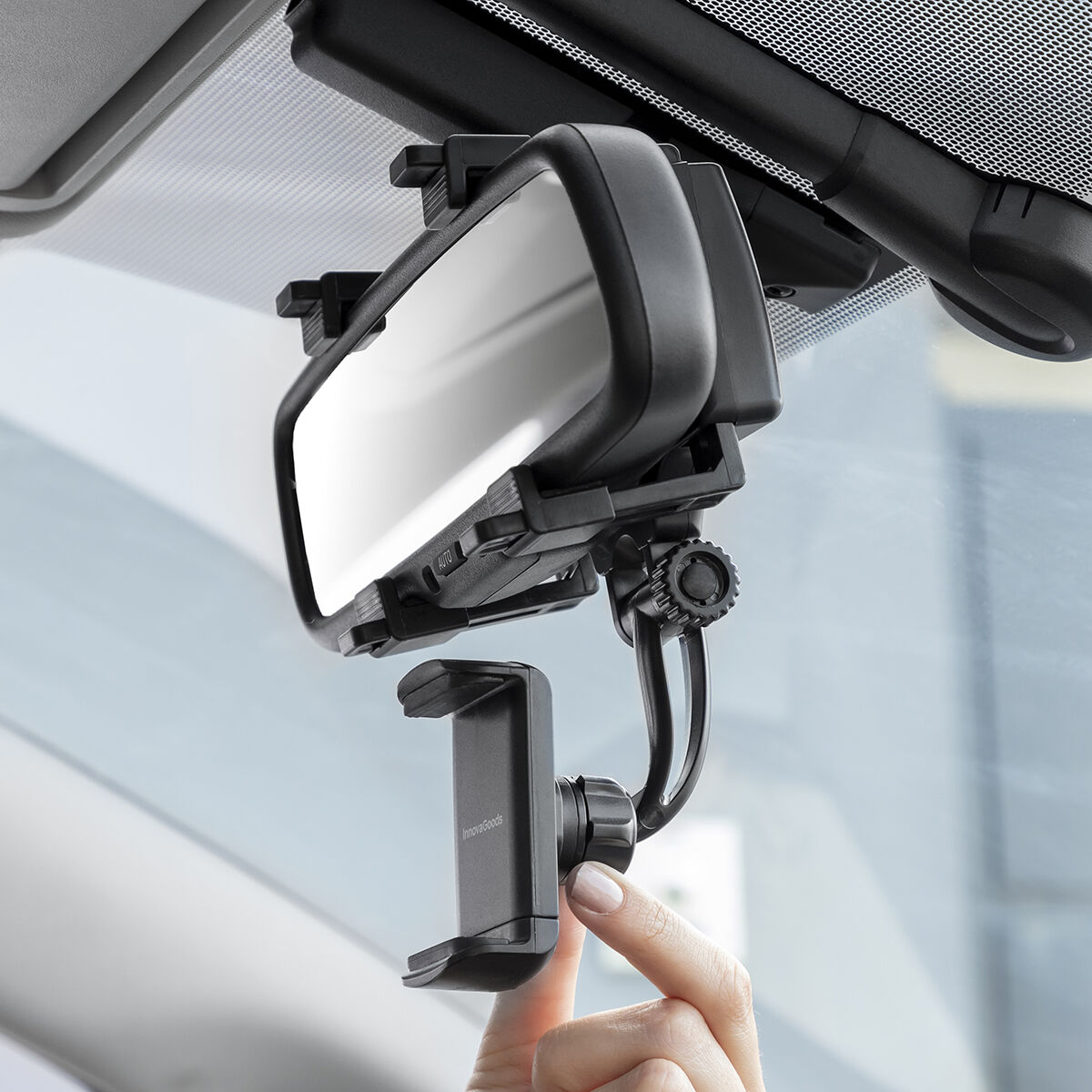 Supporto per smartphone montato sullo specchietto retrovisore dell'auto. Una mano regola il supporto.
