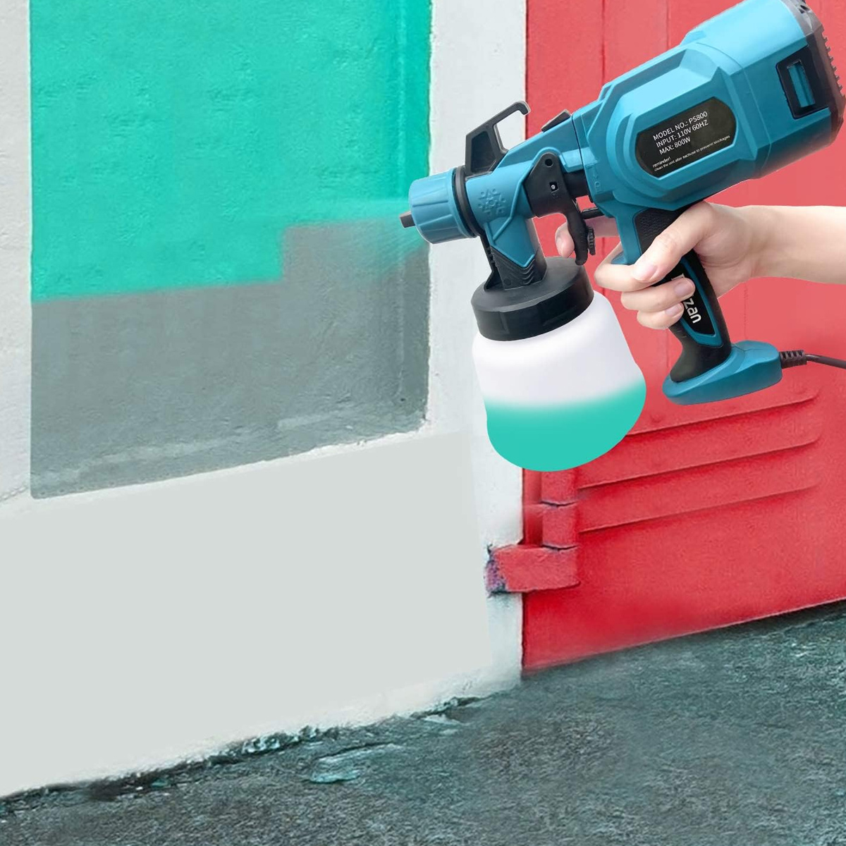 Eine Person sprüht türkisblaue Farbe mit einem blau-weißen Farbsprühgerät auf eine rote Wand.